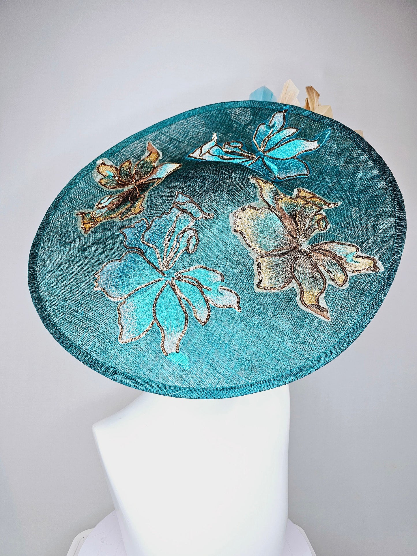 kentucky derby hat fascinator teal blue sinamay saucer with gold and teal peacock blue green feathers and teal gold embroidered flowers