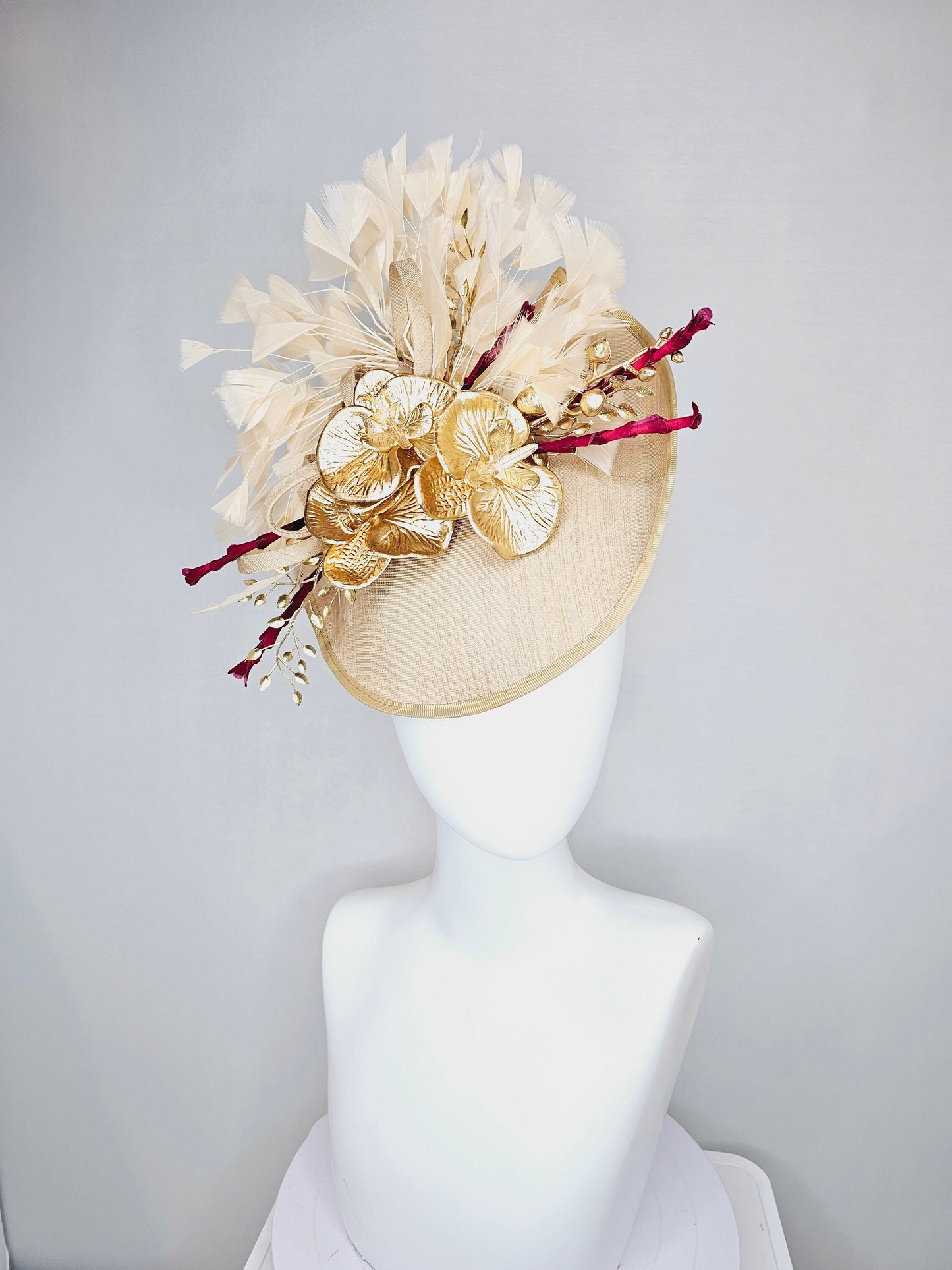 kentucky derby hat fascinator gold taupe beige shantung silk saucer with curls and gold orchids and light tan feathers with burgundy stems