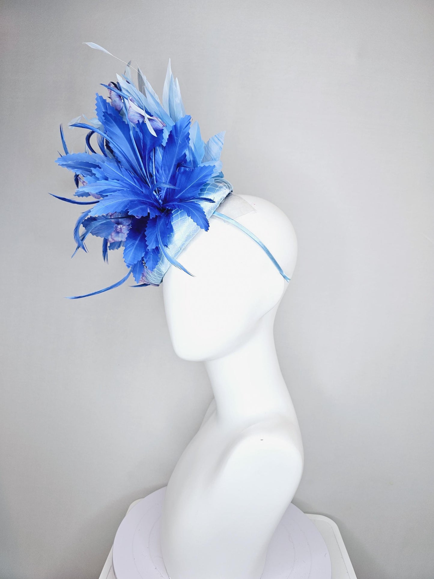 kentucky derby hat fascinator light blue satin with netting, fluffy zigzag royal blue and light blue branching feathers, purple butterflies