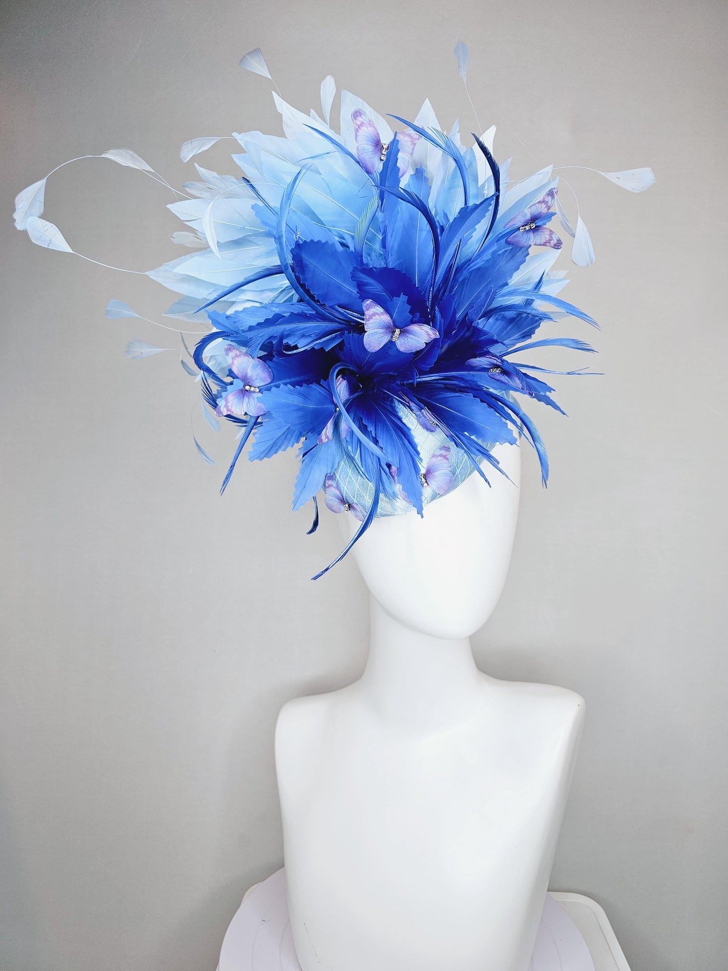 kentucky derby hat fascinator light blue satin with netting, fluffy zigzag royal blue and light blue branching feathers, purple butterflies