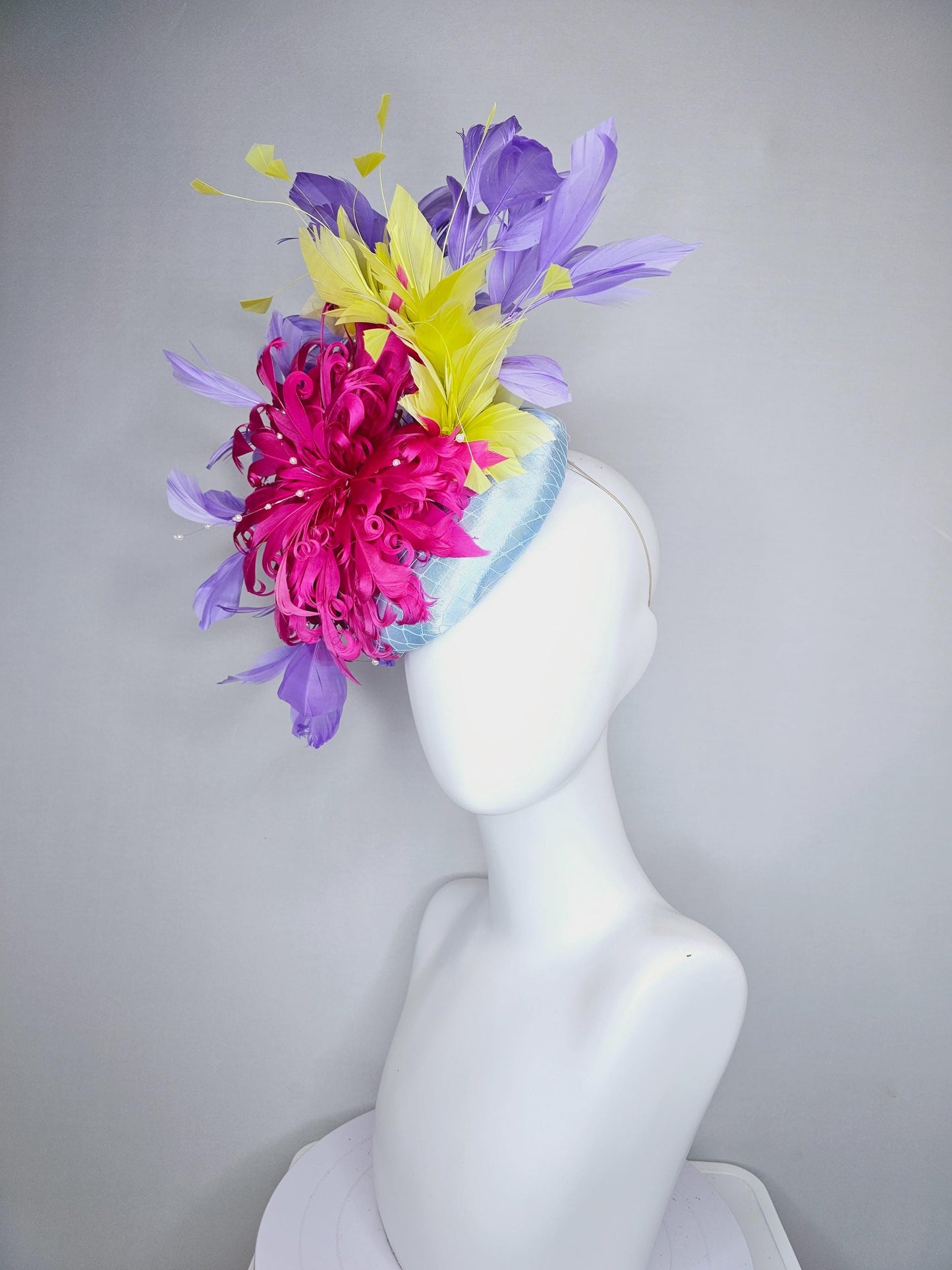 kentucky derby hat fascinator light blue satin with netting, bright pink curly feather flower, yellow and lavender purple branching feathers