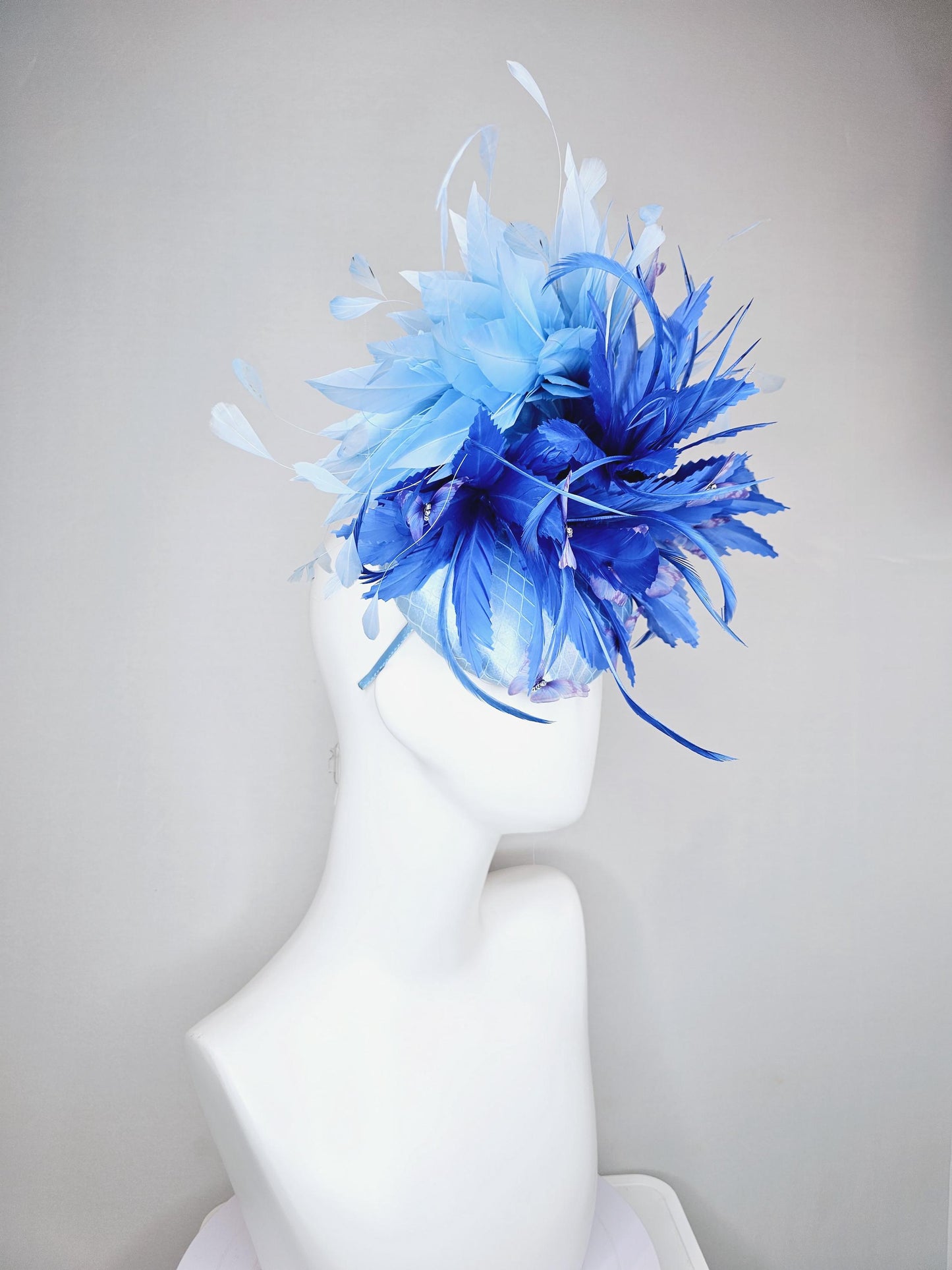 kentucky derby hat fascinator light blue satin with netting, fluffy zigzag royal blue and light blue branching feathers, purple butterflies