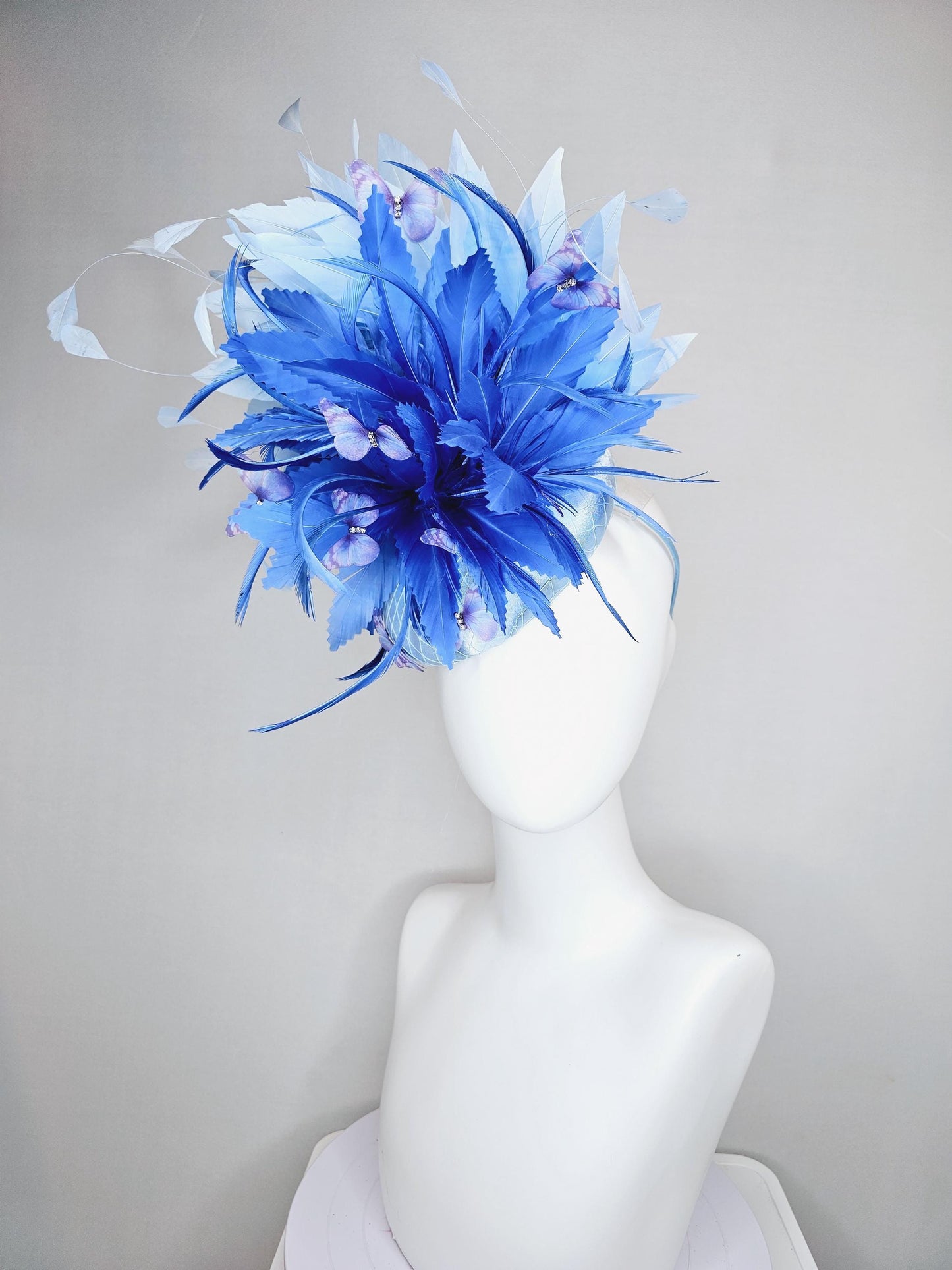 kentucky derby hat fascinator light blue satin with netting, fluffy zigzag royal blue and light blue branching feathers, purple butterflies