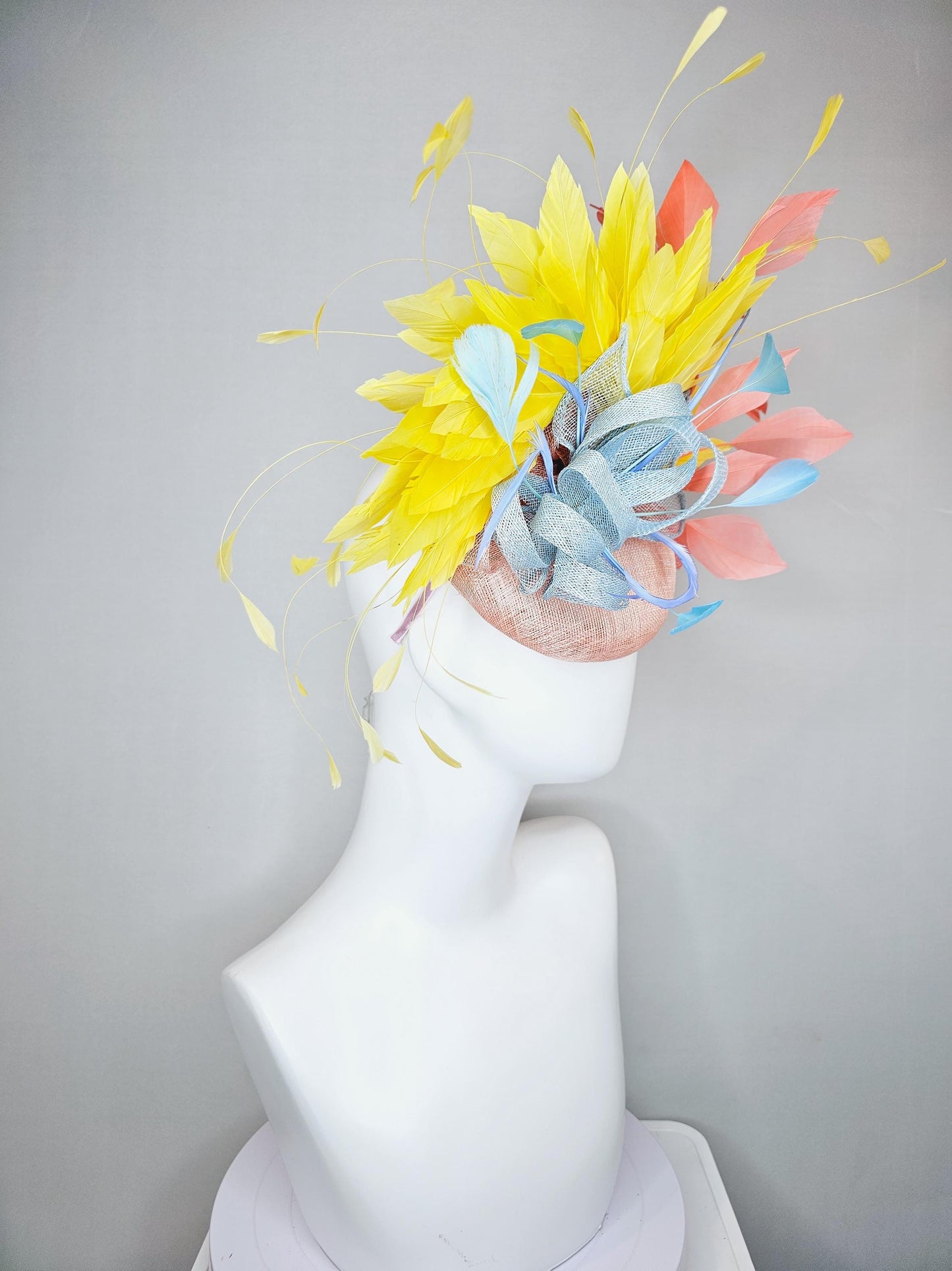 kentucky derby hat fascinator light pink sinamay with light blue sinamay bow and blue feathers, coral orange and yellow branching feathers