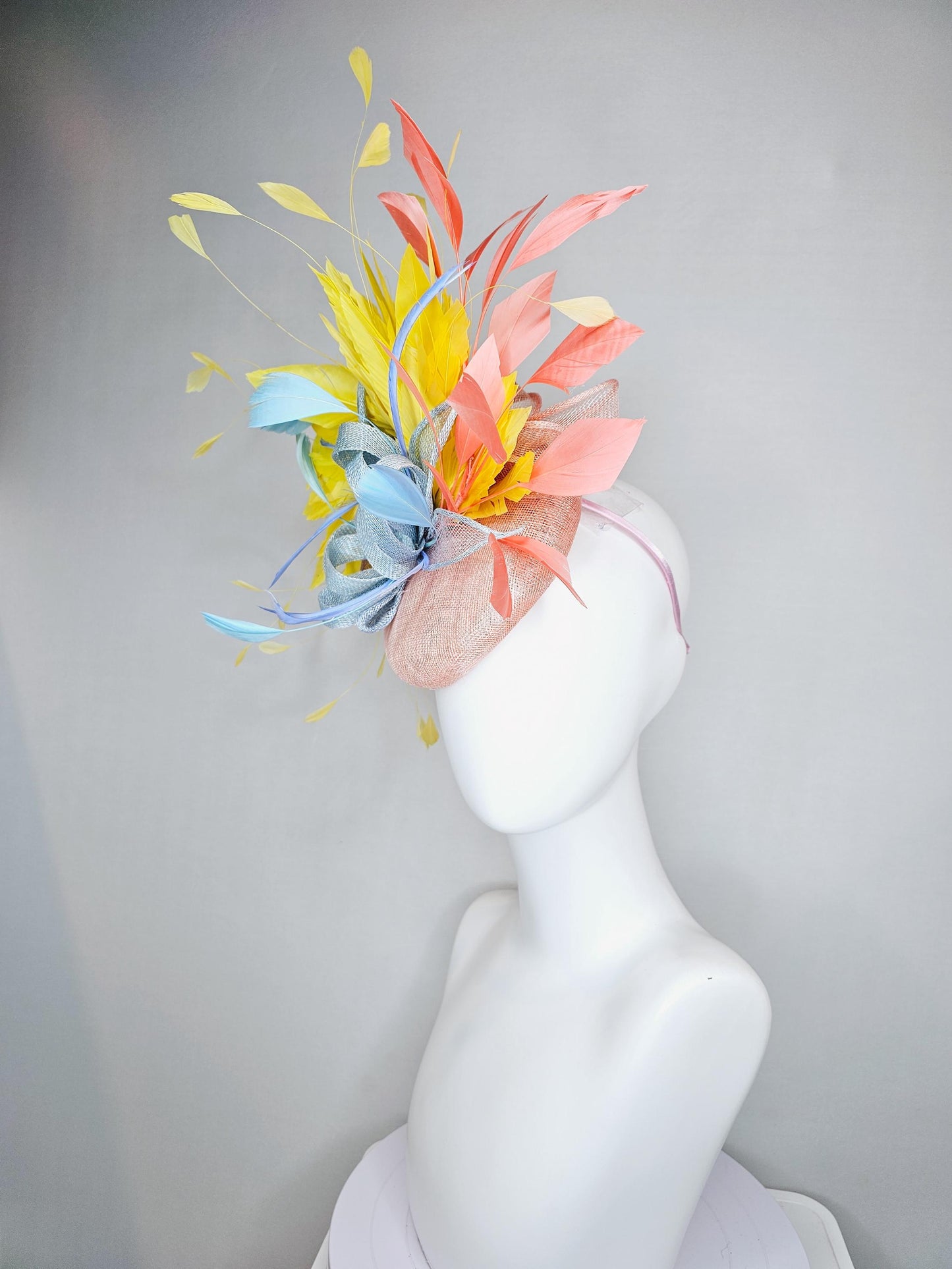 kentucky derby hat fascinator light pink sinamay with light blue sinamay bow and blue feathers, coral orange and yellow branching feathers