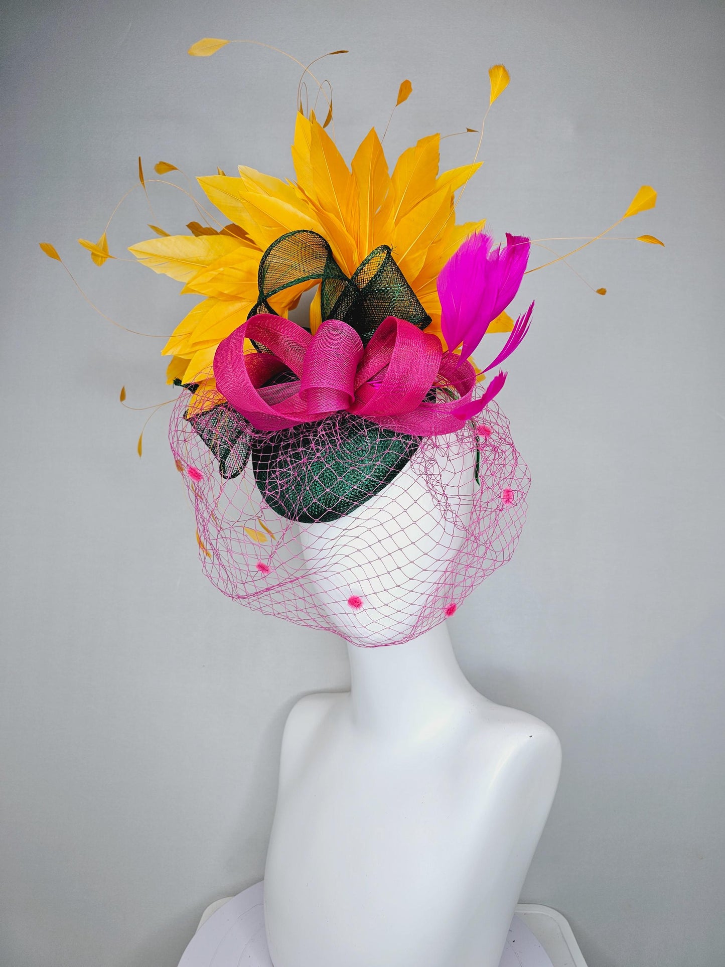 kentucky derby hat fascinator dark green sinamay with dark green and pink sinamay bow pink and yellow feathers and pink mesh veil