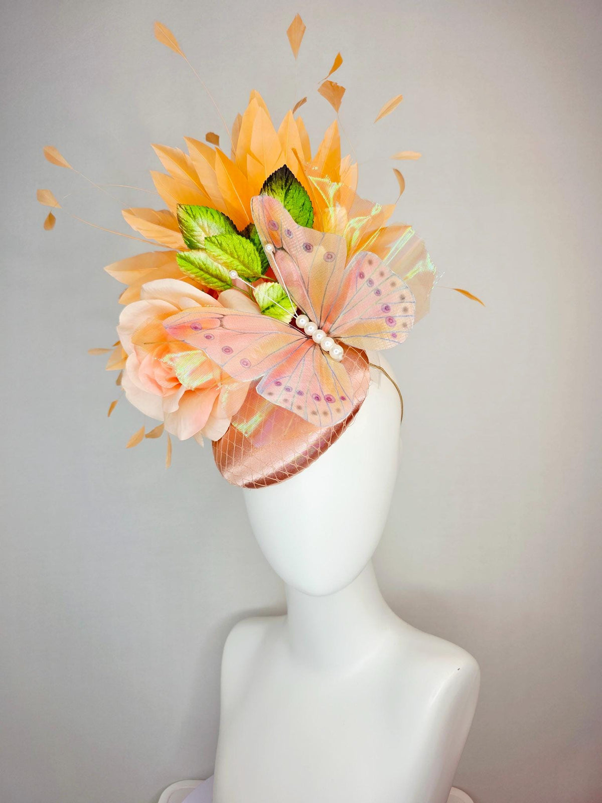 kentucky derby hat fascinator champagne pink satin with netting light pink satin rose green leaves burnt orange feathers and large butterfly