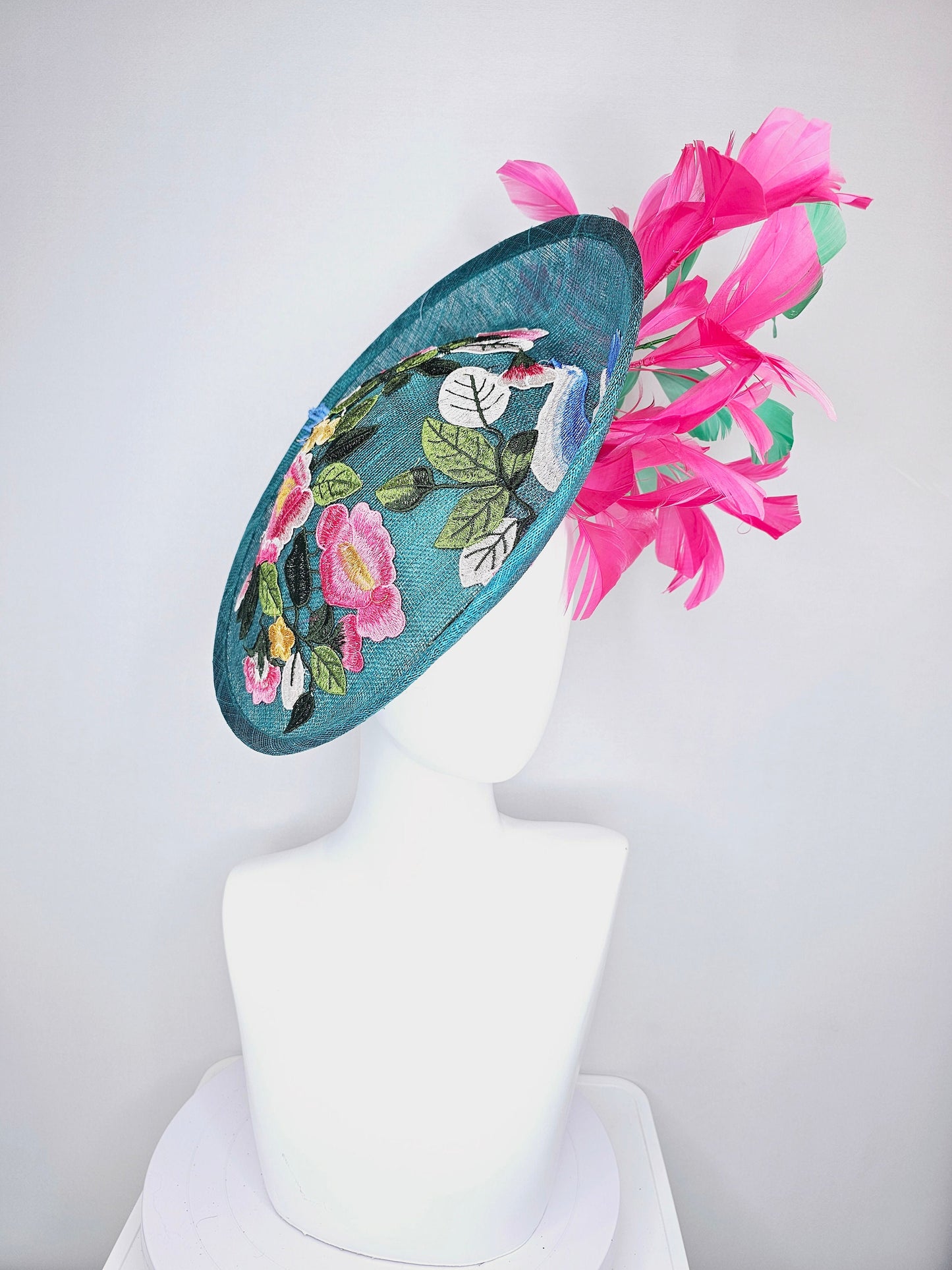 kentucky derby hat fascinator teal sinamay saucer with fuchsia pink and green feathers and yellow pink blue embroidered flowers and birds