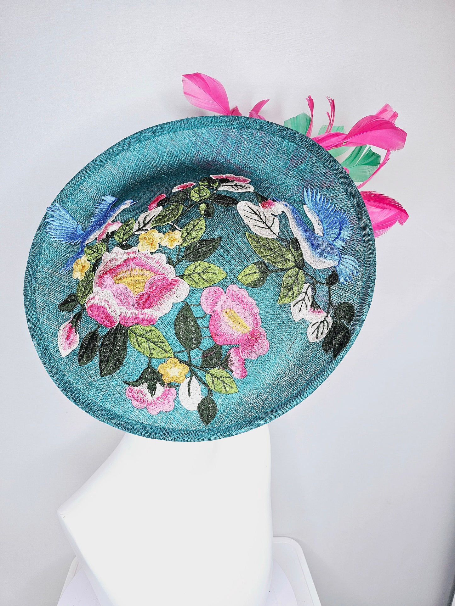 kentucky derby hat fascinator teal sinamay saucer with fuchsia pink and green feathers and yellow pink blue embroidered flowers and birds