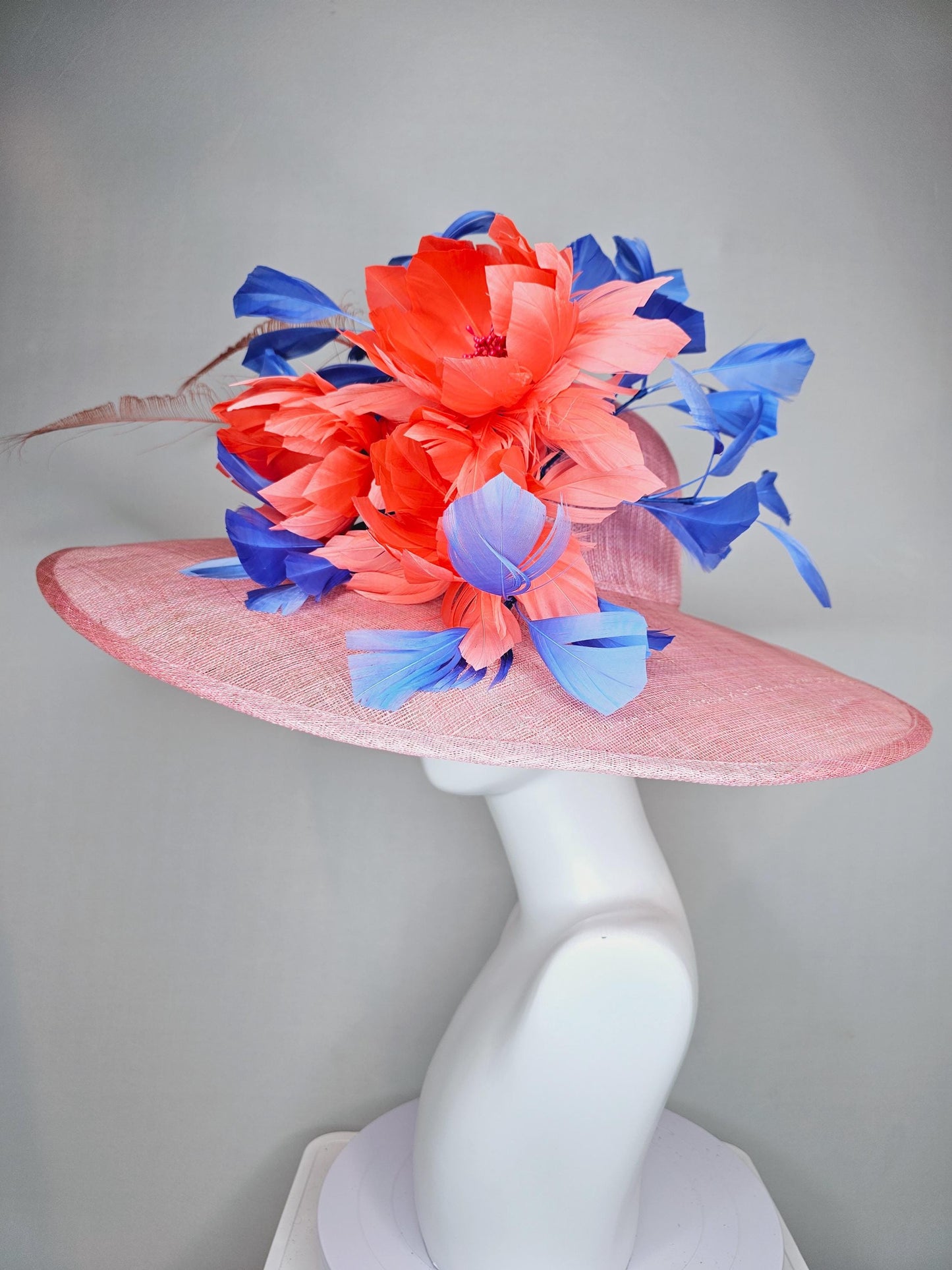 kentucky derby hat large wide brim sinamay blush pink hat with large orange coral feather flowers and royal blue branching feathers