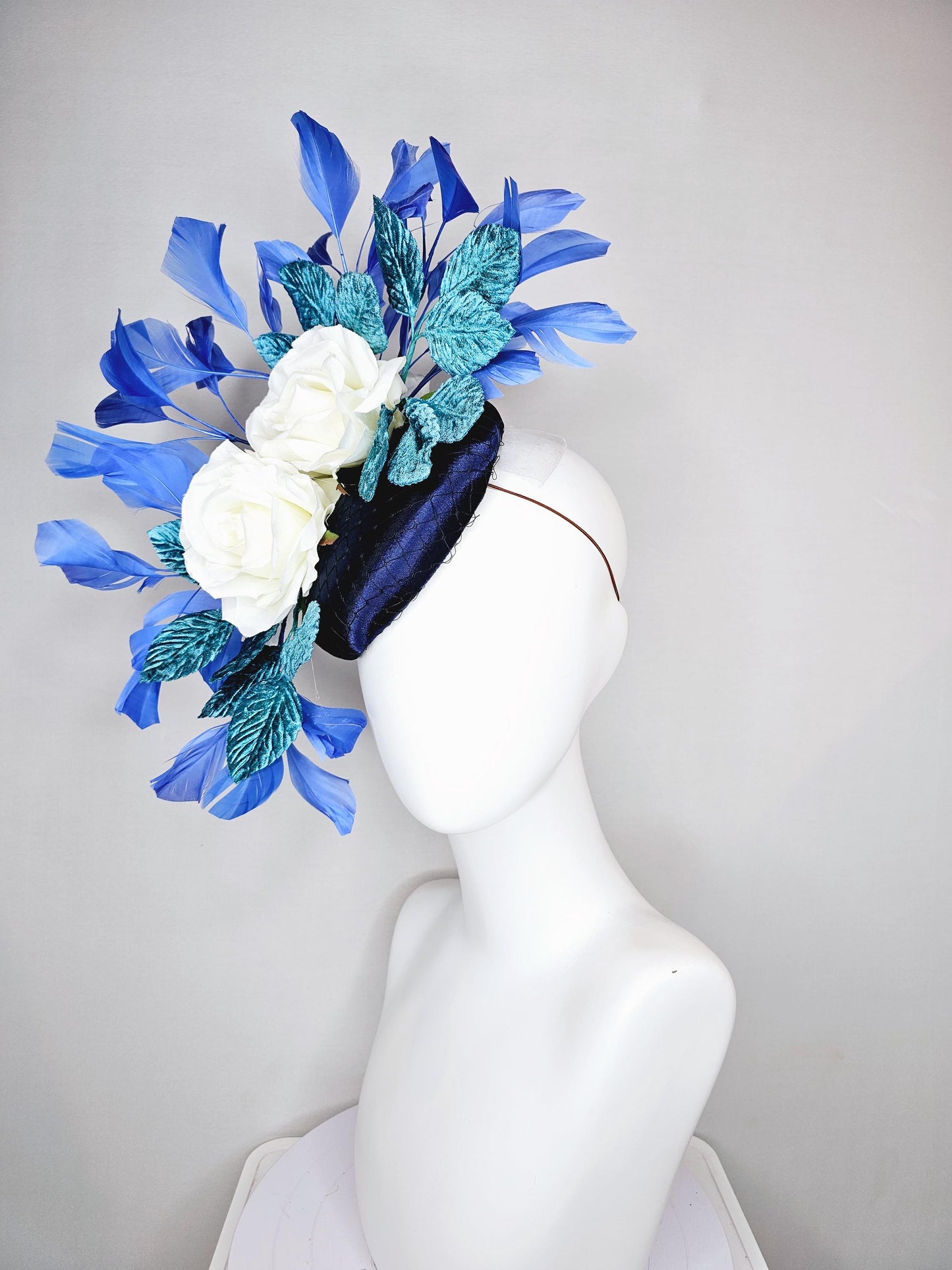 kentucky derby hat fascinator midnight navy blue satin with white silk flowers,teal blue velvet leaves,and royal blue branching feathers