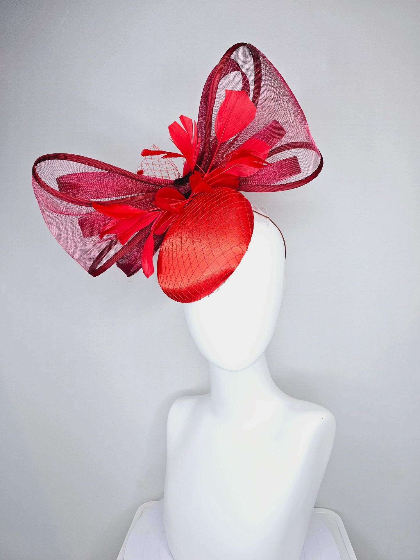 kentucky derby hat fascinator cherry red satin with netting,branching bright red feathers and large mesh burgundy wine bow