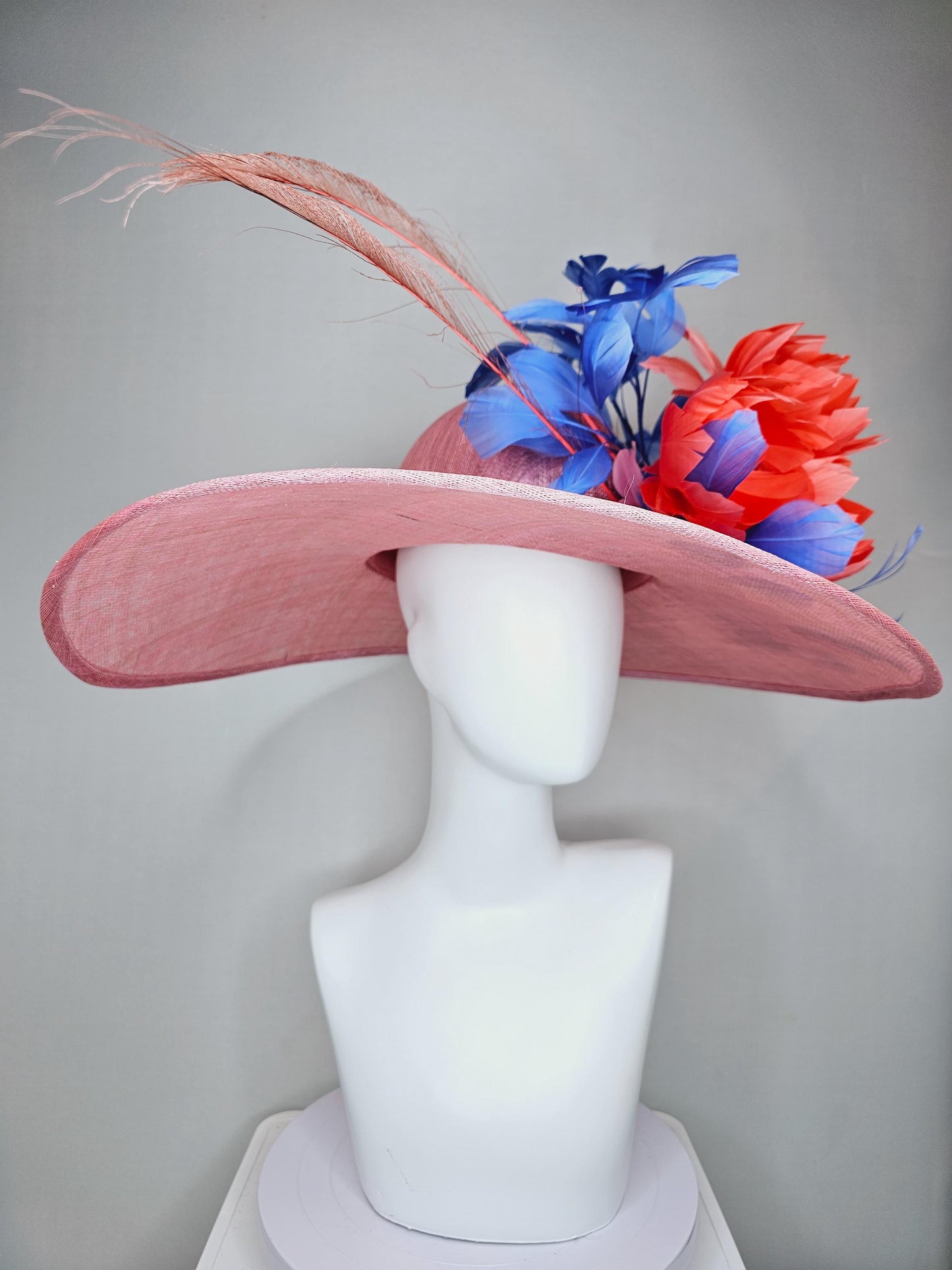 kentucky derby hat large wide brim sinamay blush pink hat with large orange coral feather flowers and royal blue branching feathers