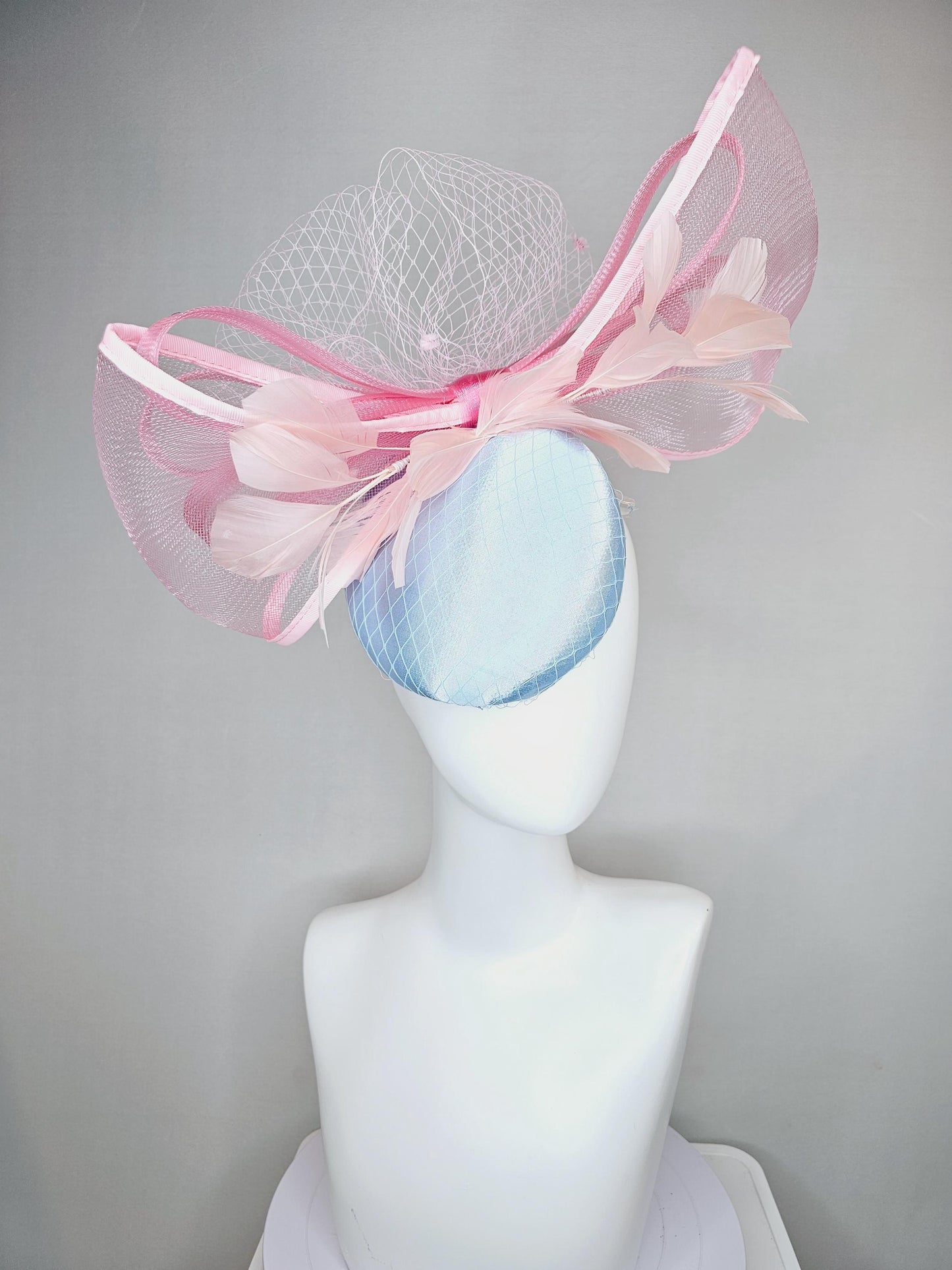 kentucky derby hat fascinator light baby blue satin with netting, branching light blush pink feathers and large mesh blush pink bow