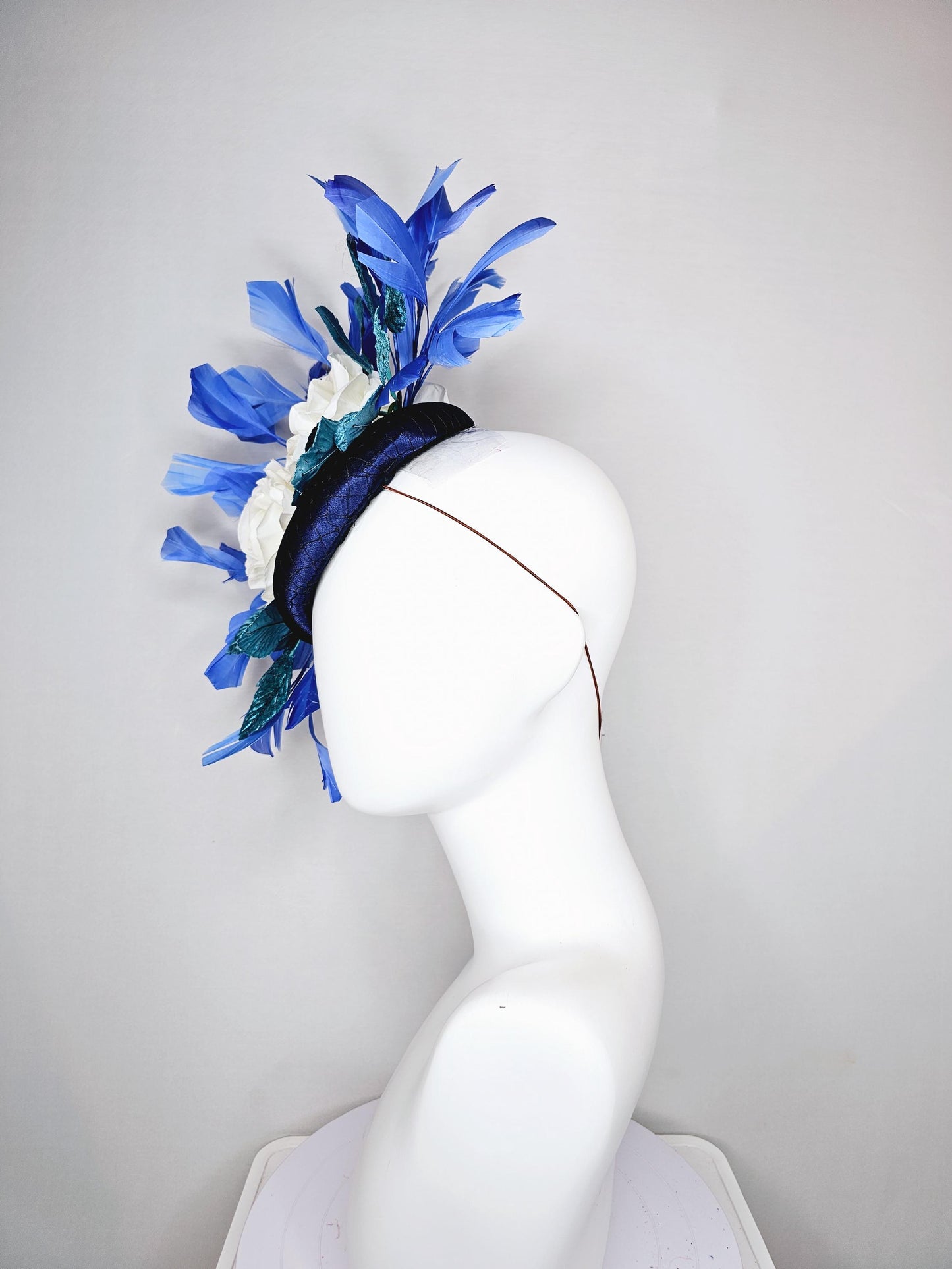 kentucky derby hat fascinator midnight navy blue satin with white silk flowers,teal blue velvet leaves,and royal blue branching feathers