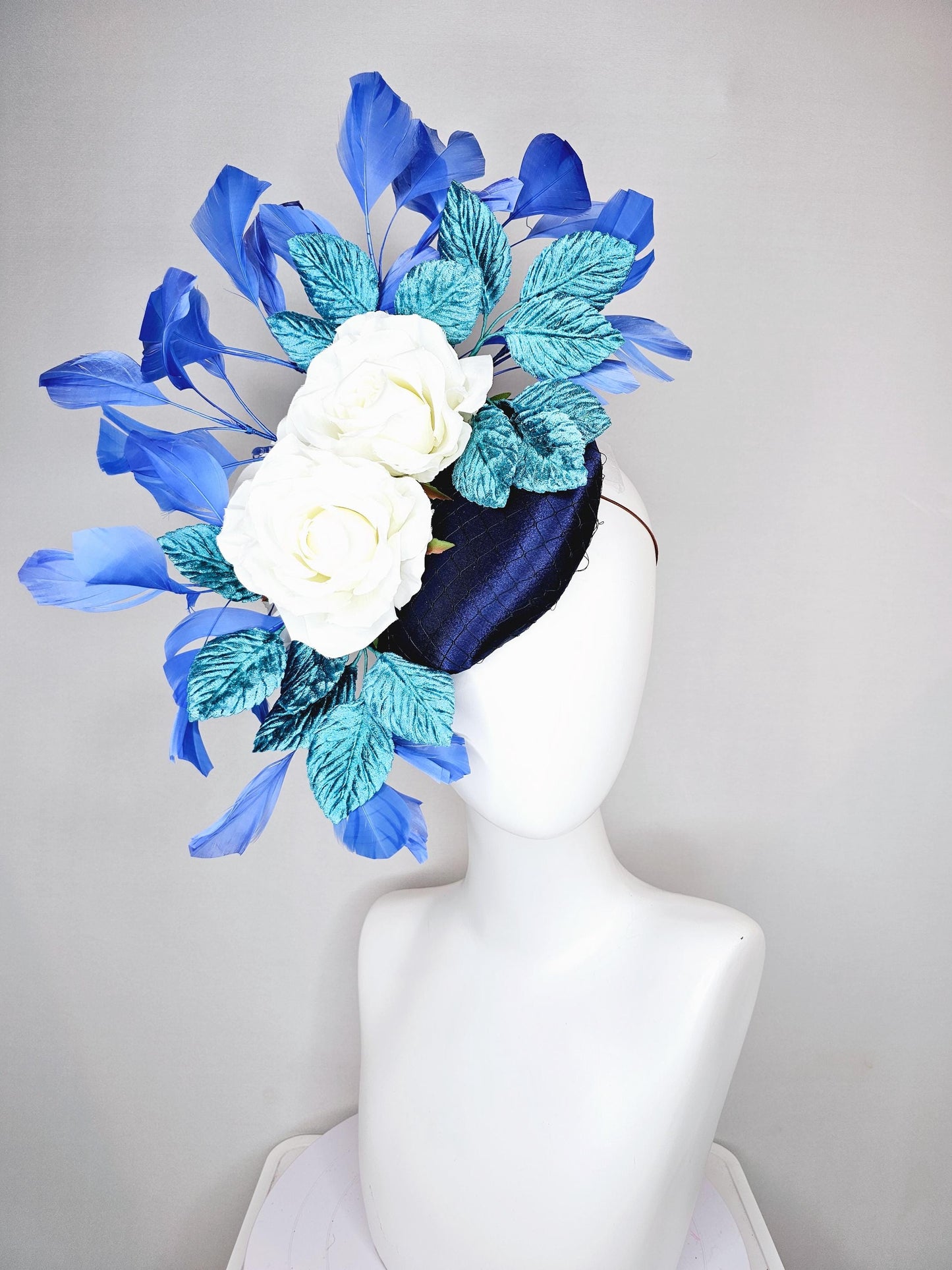 kentucky derby hat fascinator midnight navy blue satin with white silk flowers,teal blue velvet leaves,and royal blue branching feathers