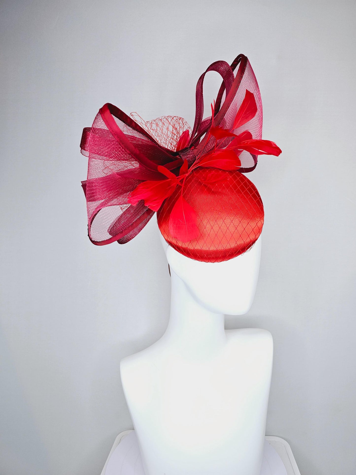 kentucky derby hat fascinator cherry red satin with netting,branching bright red feathers and large mesh burgundy wine bow