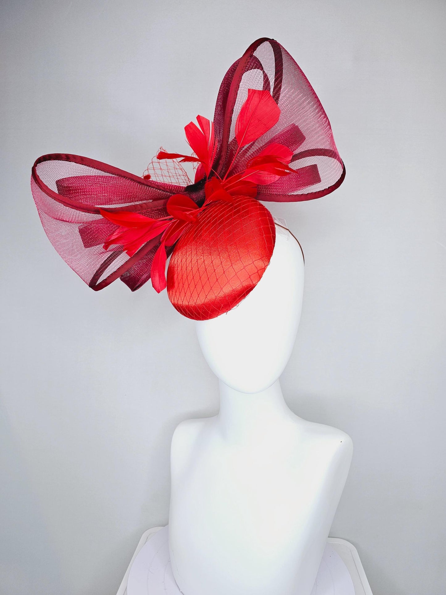 kentucky derby hat fascinator cherry red satin with netting,branching bright red feathers and large mesh burgundy wine bow