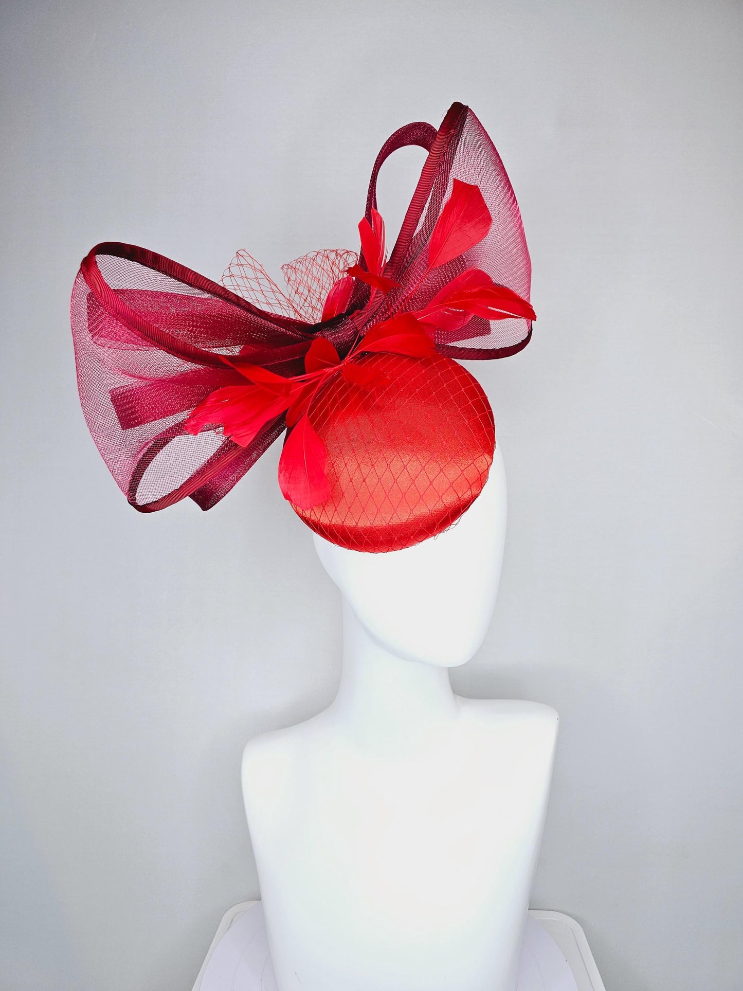 kentucky derby hat fascinator cherry red satin with netting,branching bright red feathers and large mesh burgundy wine bow