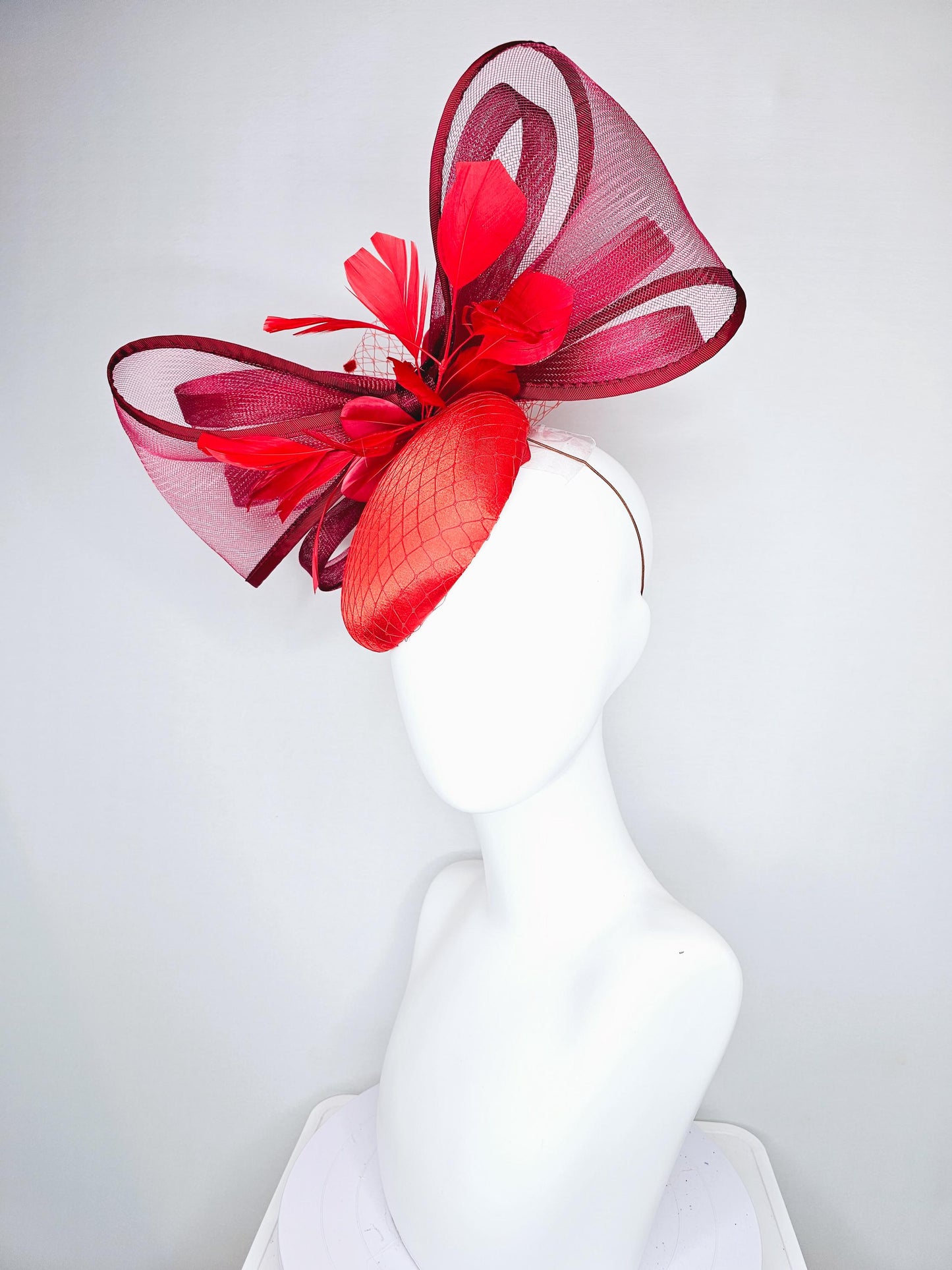 kentucky derby hat fascinator cherry red satin with netting,branching bright red feathers and large mesh burgundy wine bow