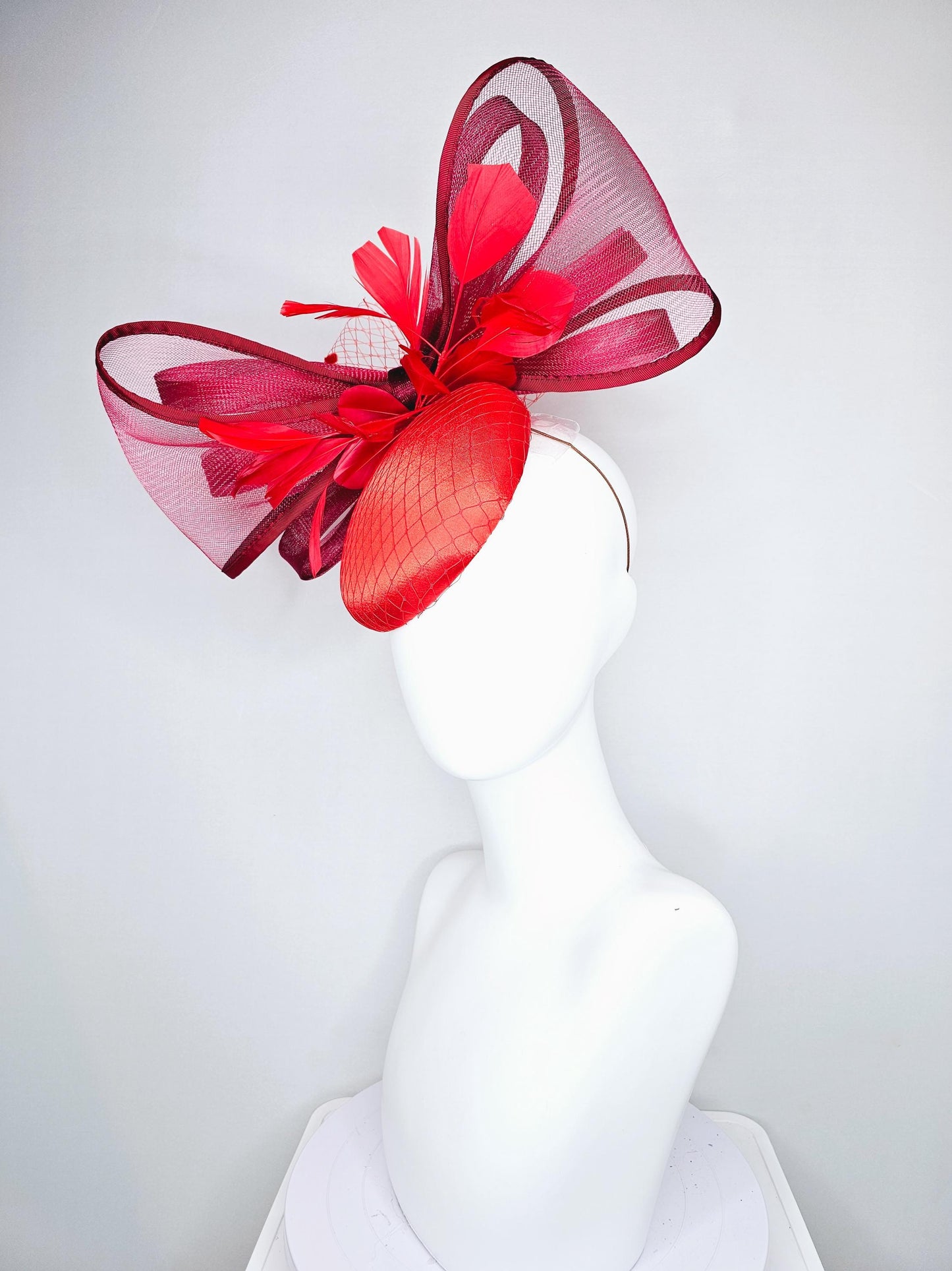 kentucky derby hat fascinator cherry red satin with netting,branching bright red feathers and large mesh burgundy wine bow