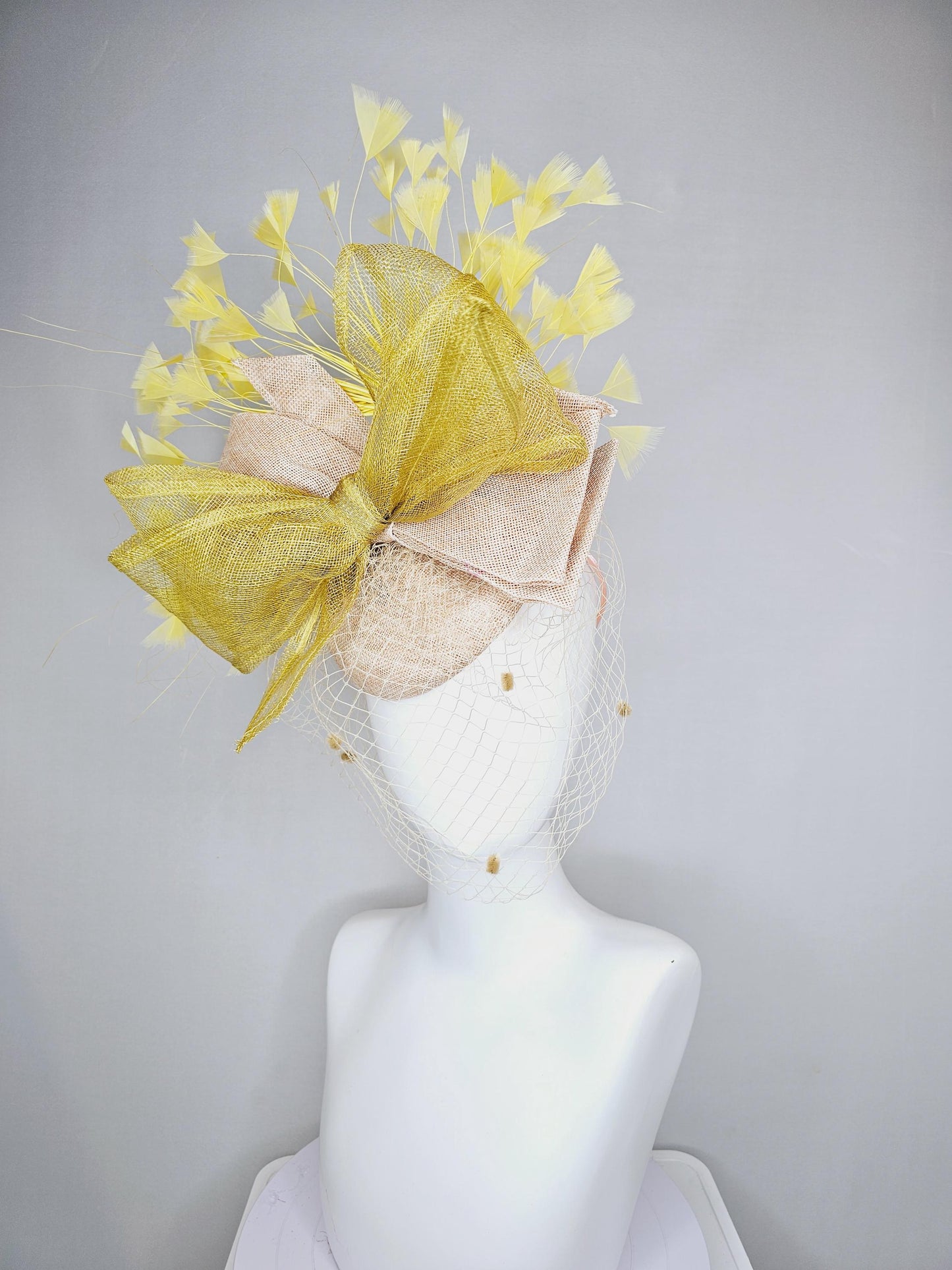 kentucky derby hat fascinator neutral beige sinamay with mesh veil, large mustard yellow mesh ribbon bow, light yellow branching feathers