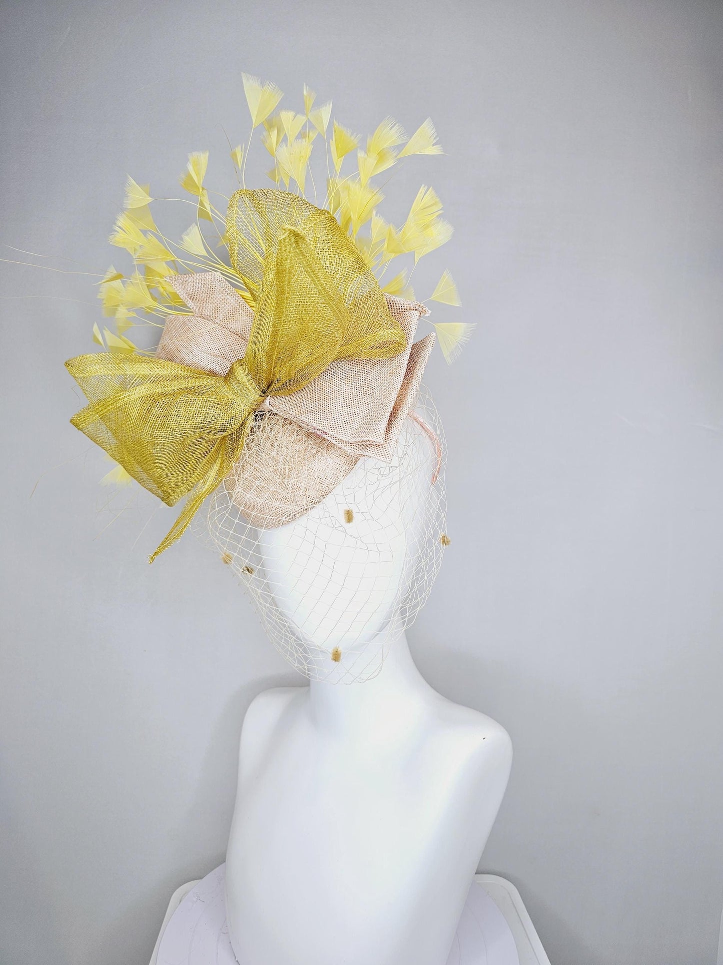 kentucky derby hat fascinator neutral beige sinamay with mesh veil, large mustard yellow mesh ribbon bow, light yellow branching feathers