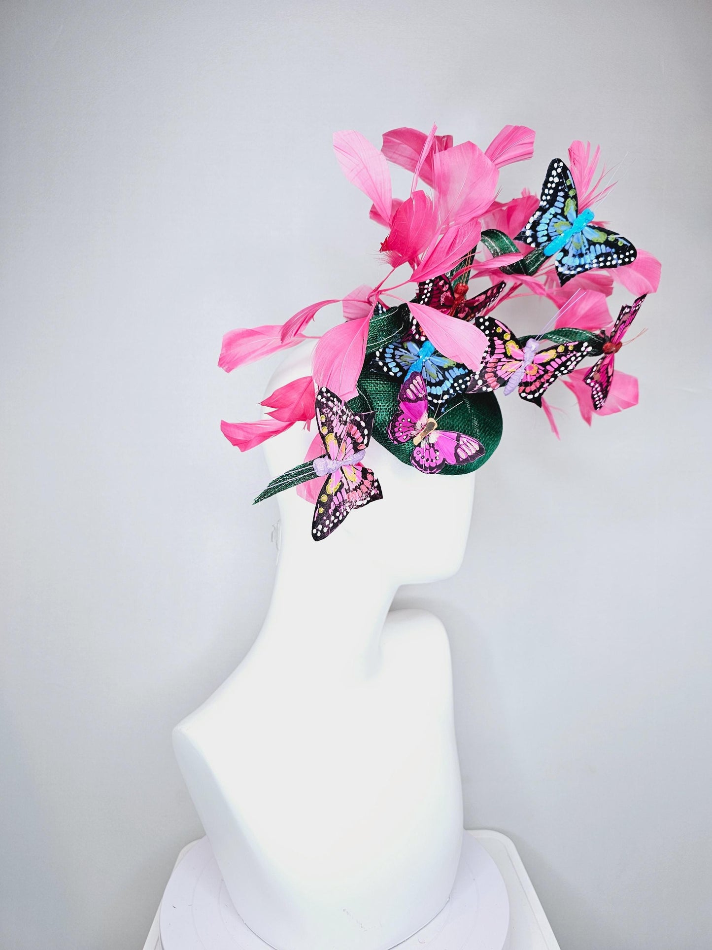 kentucky derby hat fascinator dark green sinamay with curls,pink branching feathers,colorful rainbow blue,pink,purple painted butterflies