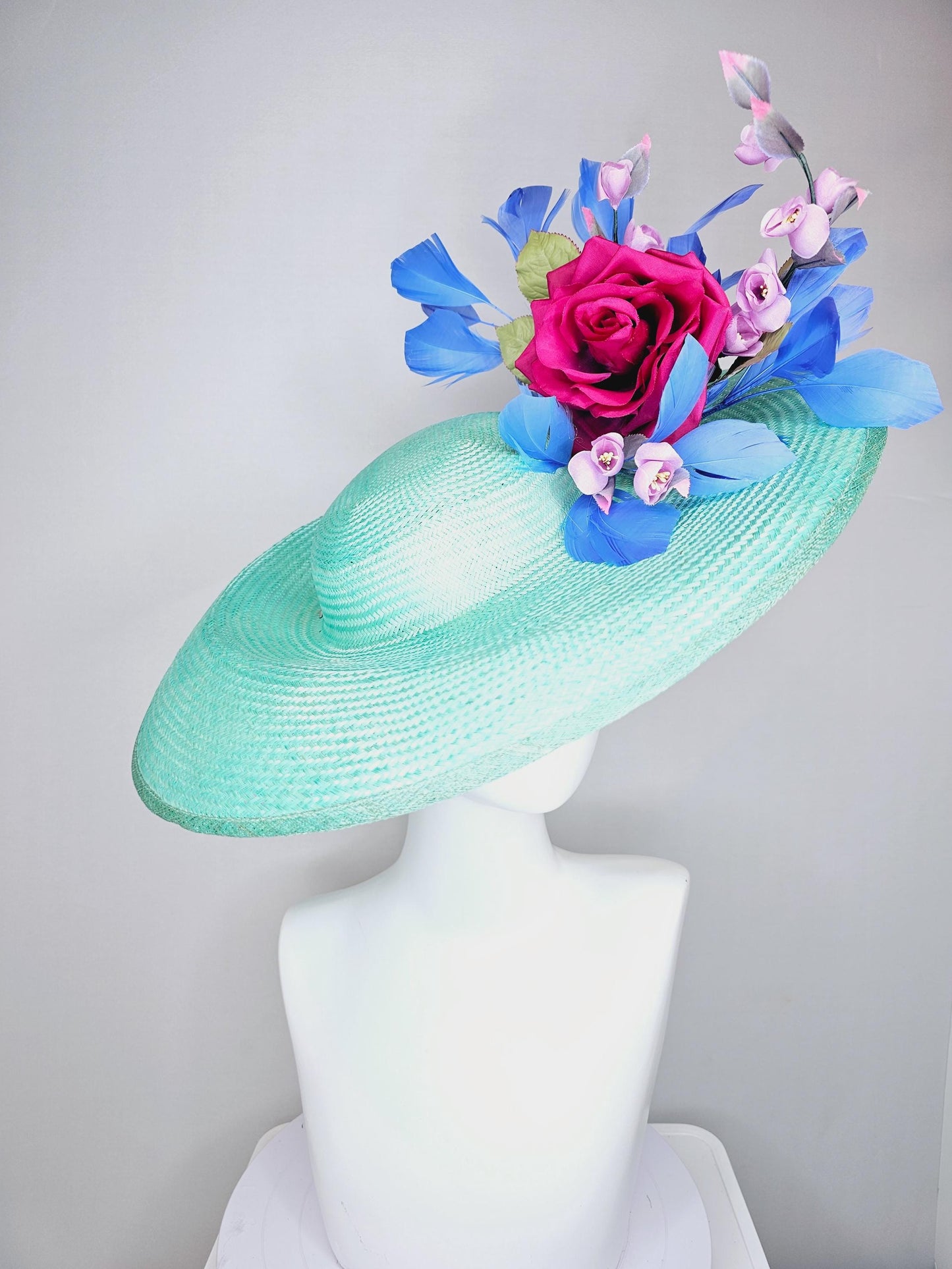 kentucky derby hat wide brim straw in aqua mint green with pink satin rose and lilac lavender purple satin rose stems cobalt blue feathers