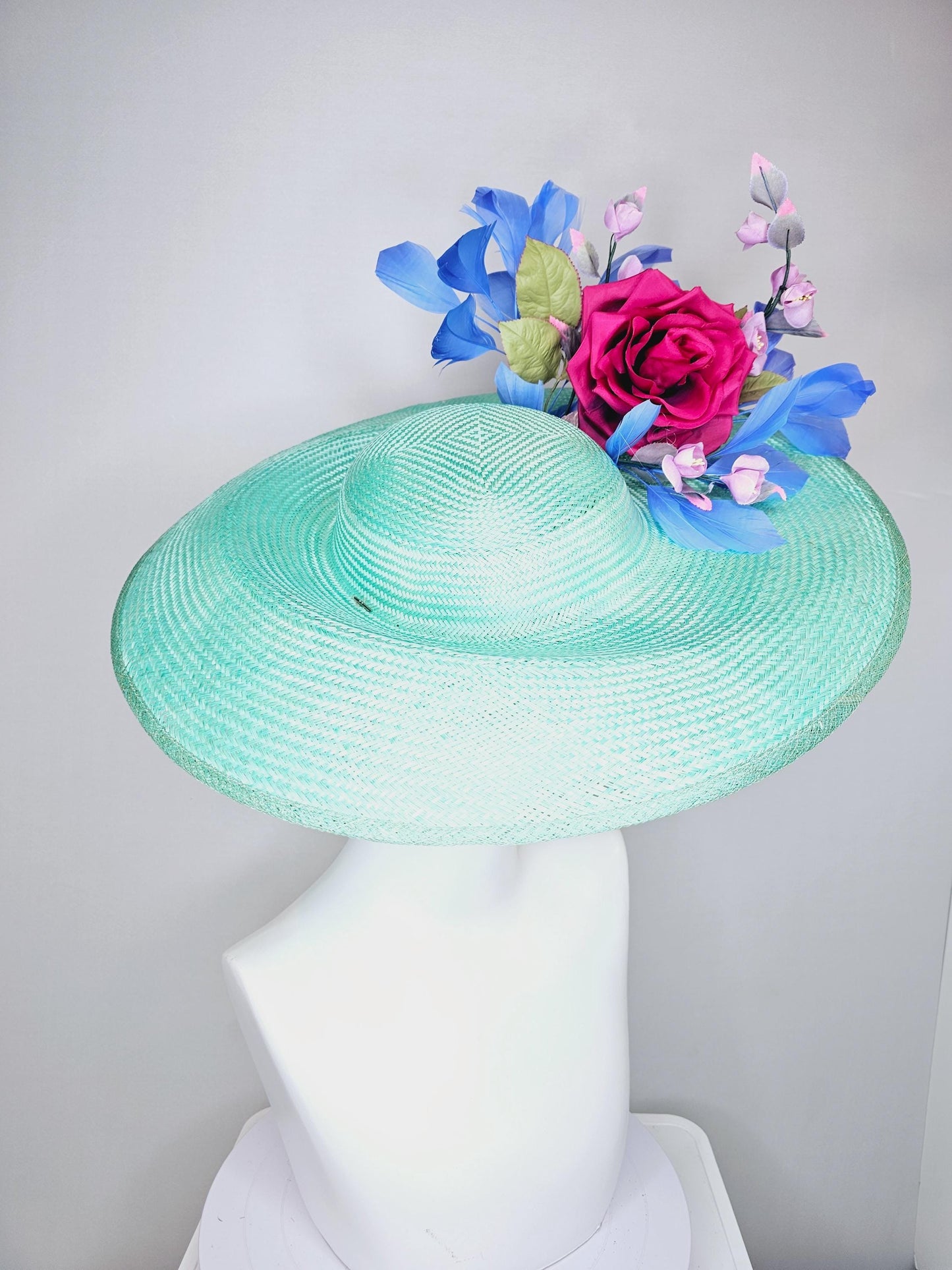 kentucky derby hat wide brim straw in aqua mint green with pink satin rose and lilac lavender purple satin rose stems cobalt blue feathers