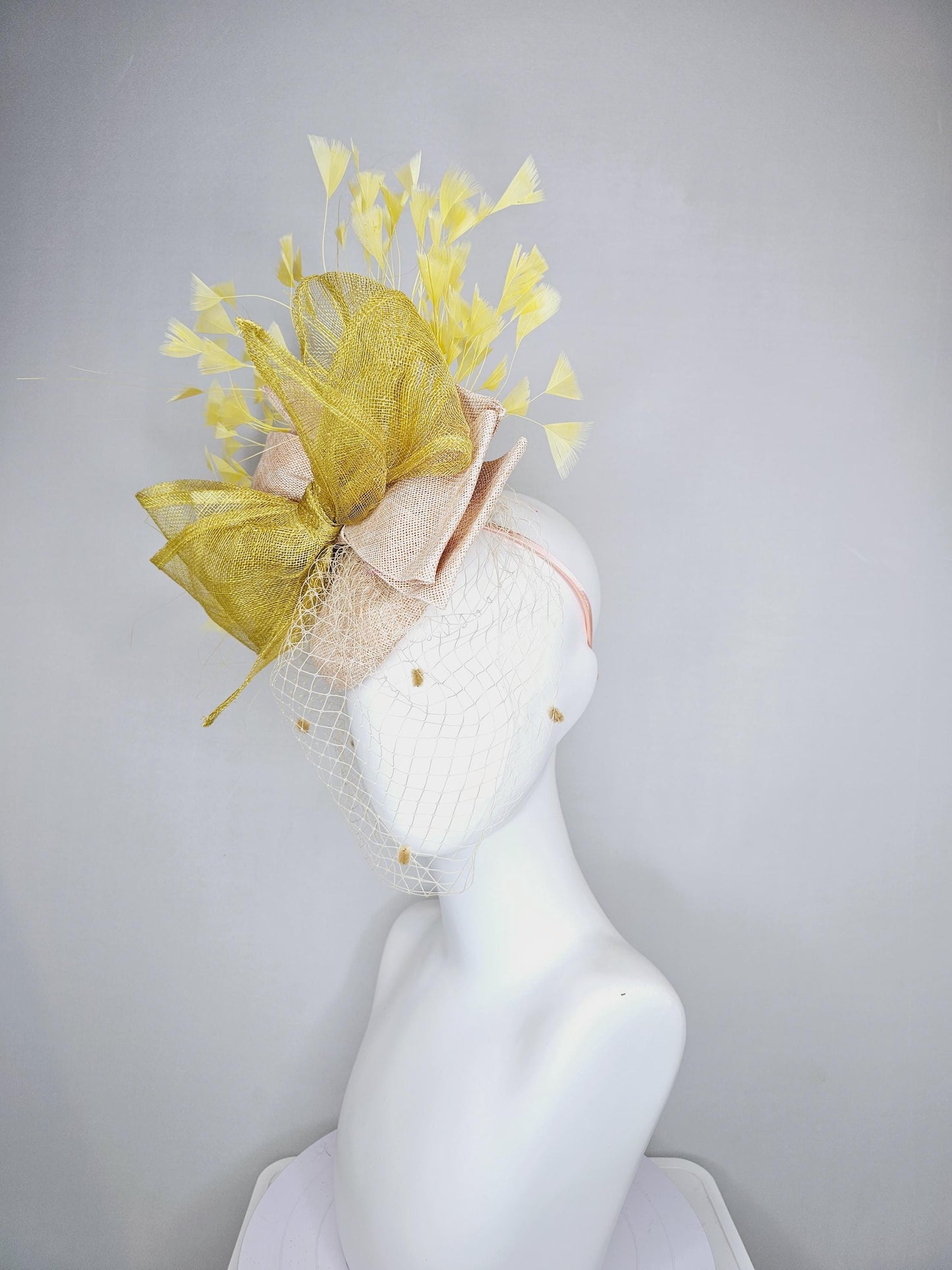 kentucky derby hat fascinator neutral beige sinamay with mesh veil, large mustard yellow mesh ribbon bow, light yellow branching feathers