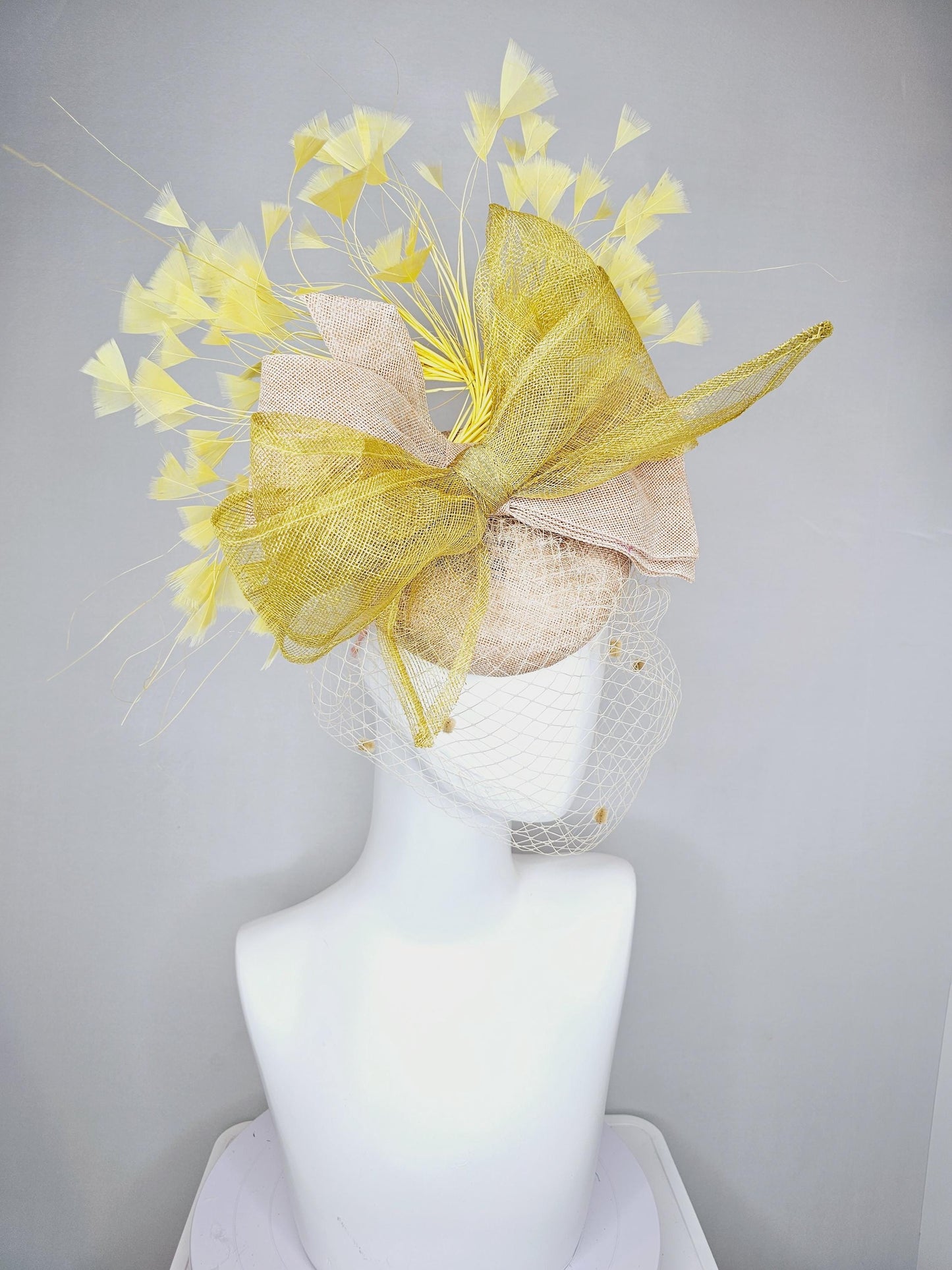 kentucky derby hat fascinator neutral beige sinamay with mesh veil, large mustard yellow mesh ribbon bow, light yellow branching feathers