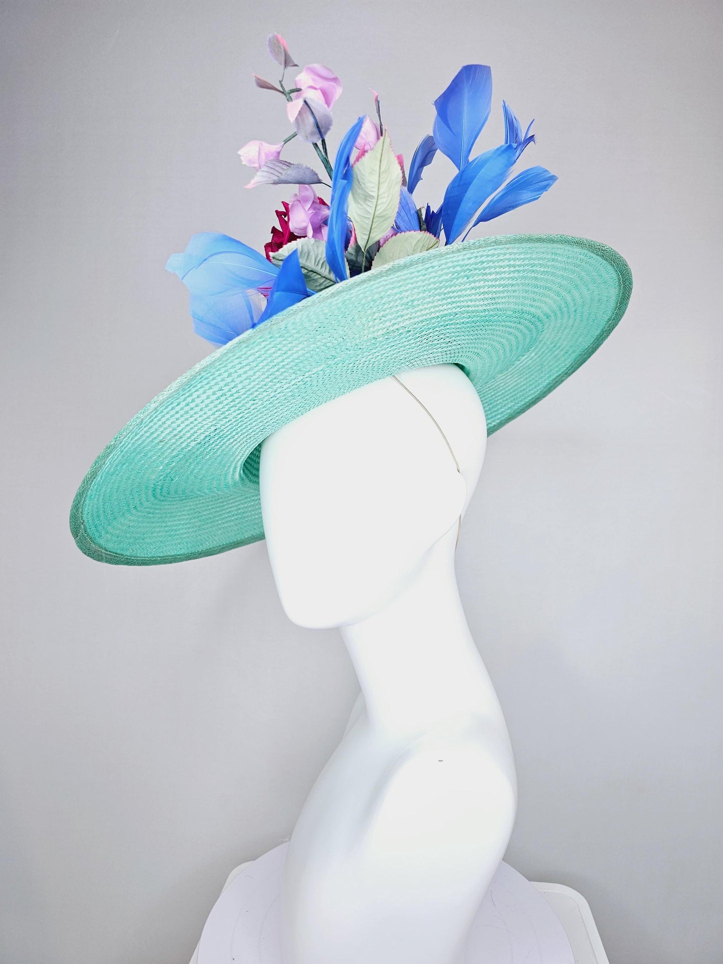 kentucky derby hat wide brim straw in aqua mint green with pink satin rose and lilac lavender purple satin rose stems cobalt blue feathers