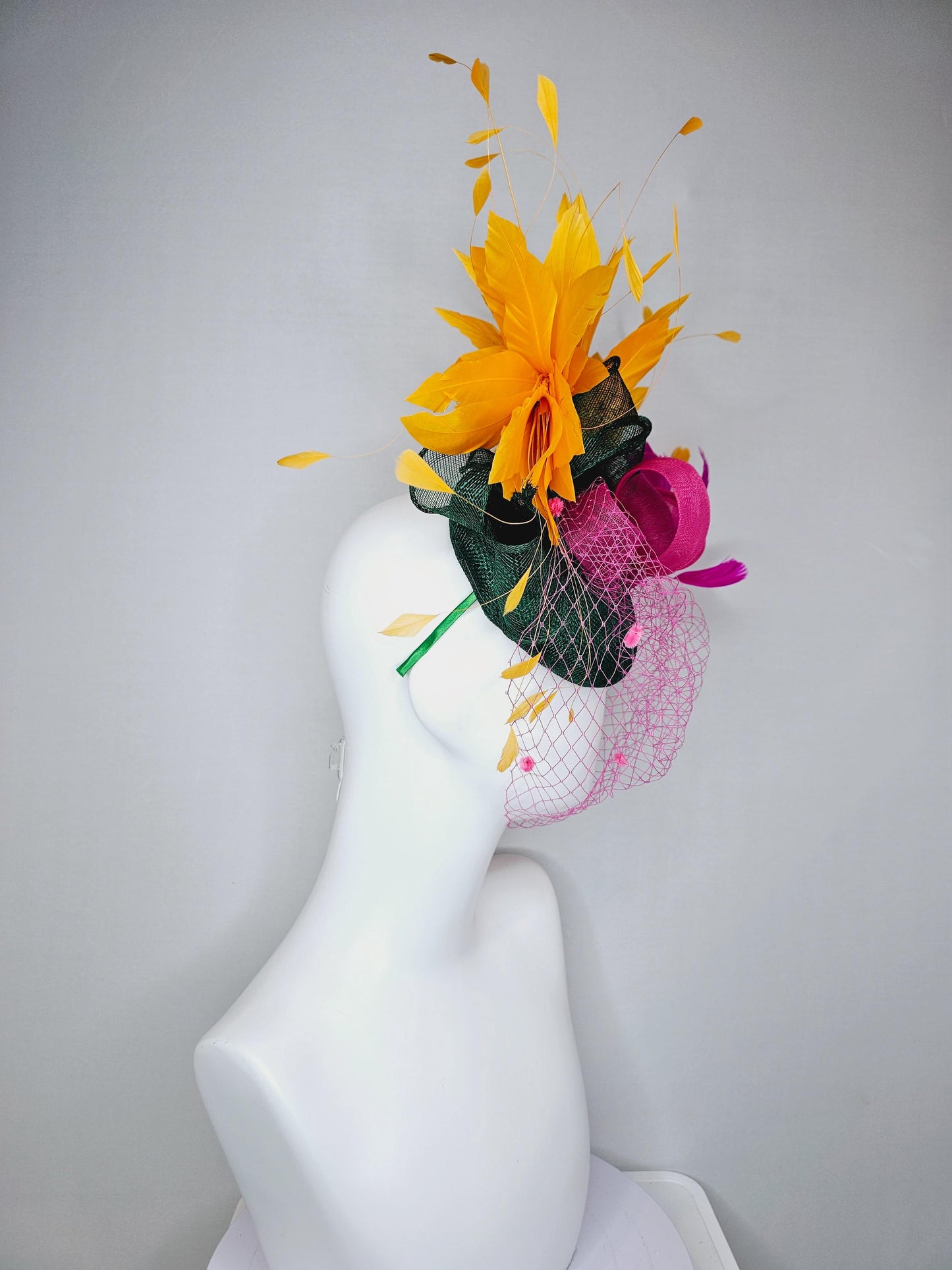 kentucky derby hat fascinator dark green sinamay with dark green and pink sinamay bow pink and yellow feathers and pink mesh veil