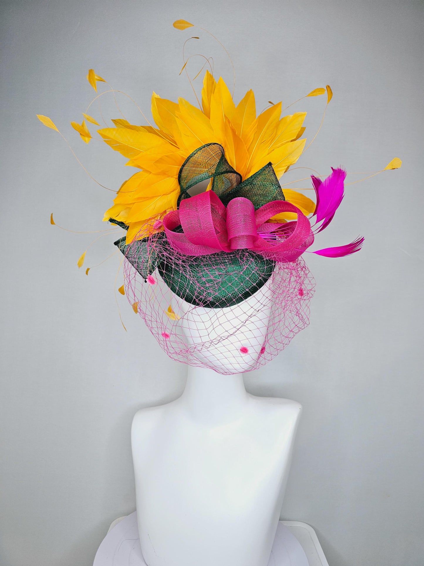 kentucky derby hat fascinator dark green sinamay with dark green and pink sinamay bow pink and yellow feathers and pink mesh veil