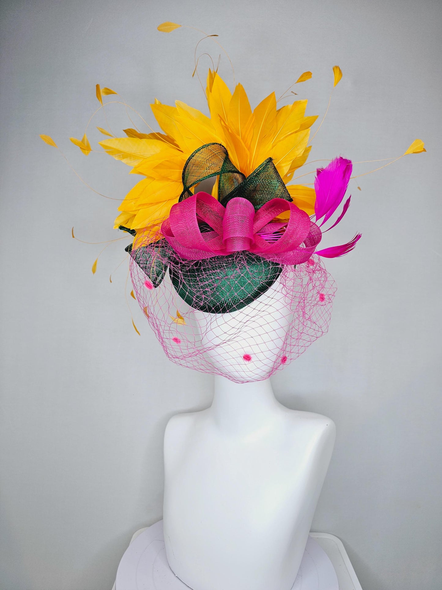 kentucky derby hat fascinator dark green sinamay with dark green and pink sinamay bow pink and yellow feathers and pink mesh veil