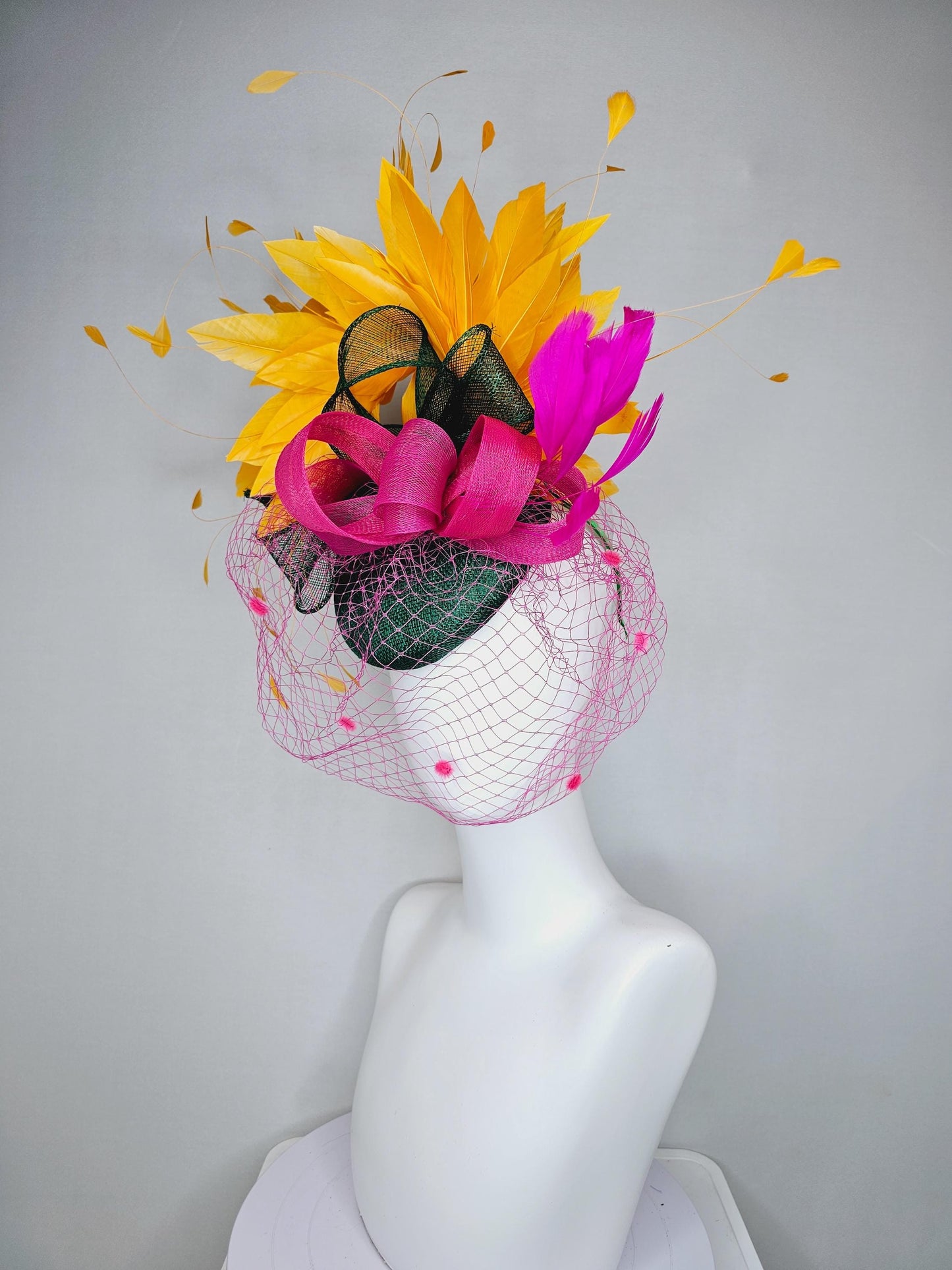 kentucky derby hat fascinator dark green sinamay with dark green and pink sinamay bow pink and yellow feathers and pink mesh veil