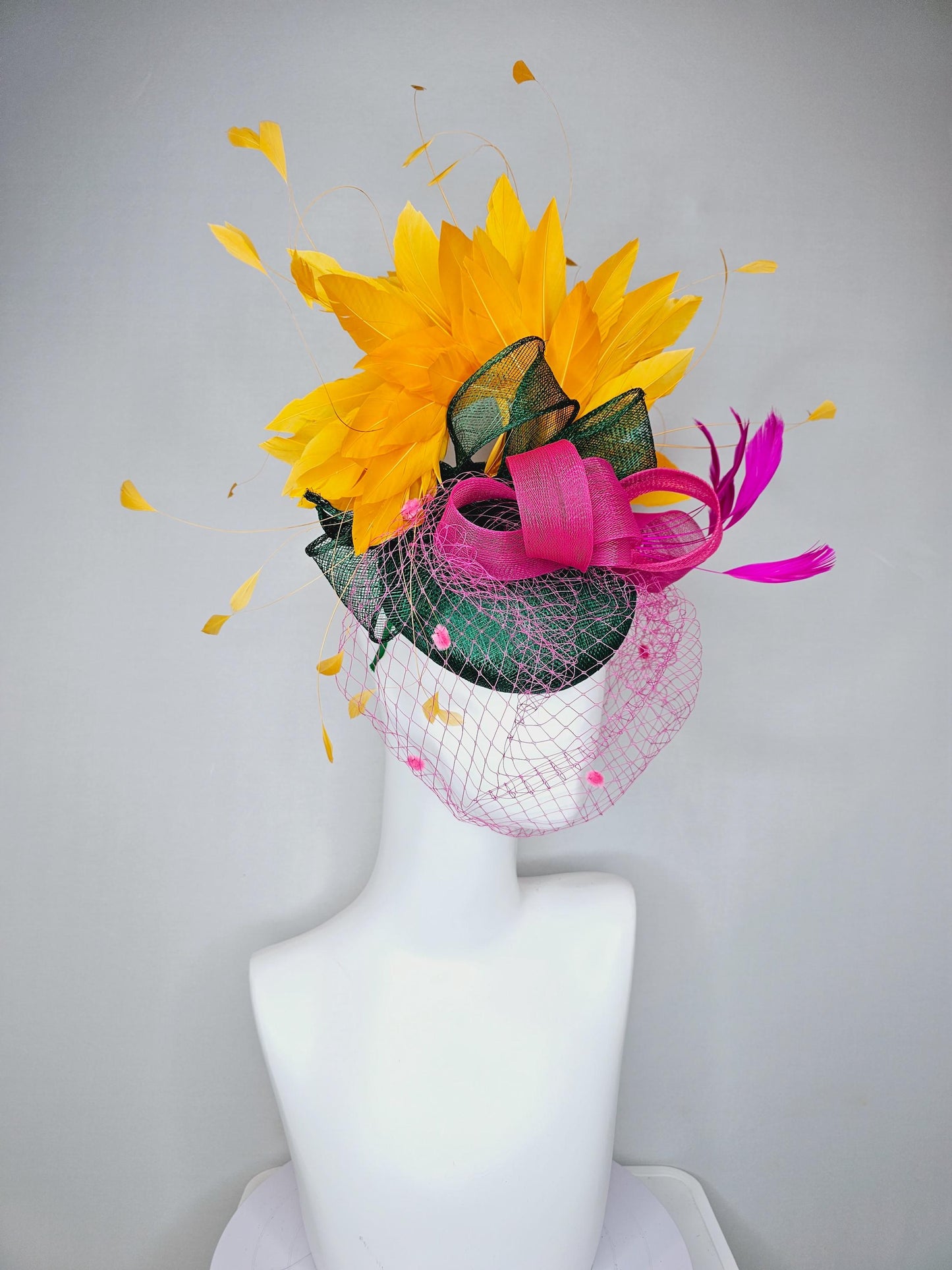 kentucky derby hat fascinator dark green sinamay with dark green and pink sinamay bow pink and yellow feathers and pink mesh veil