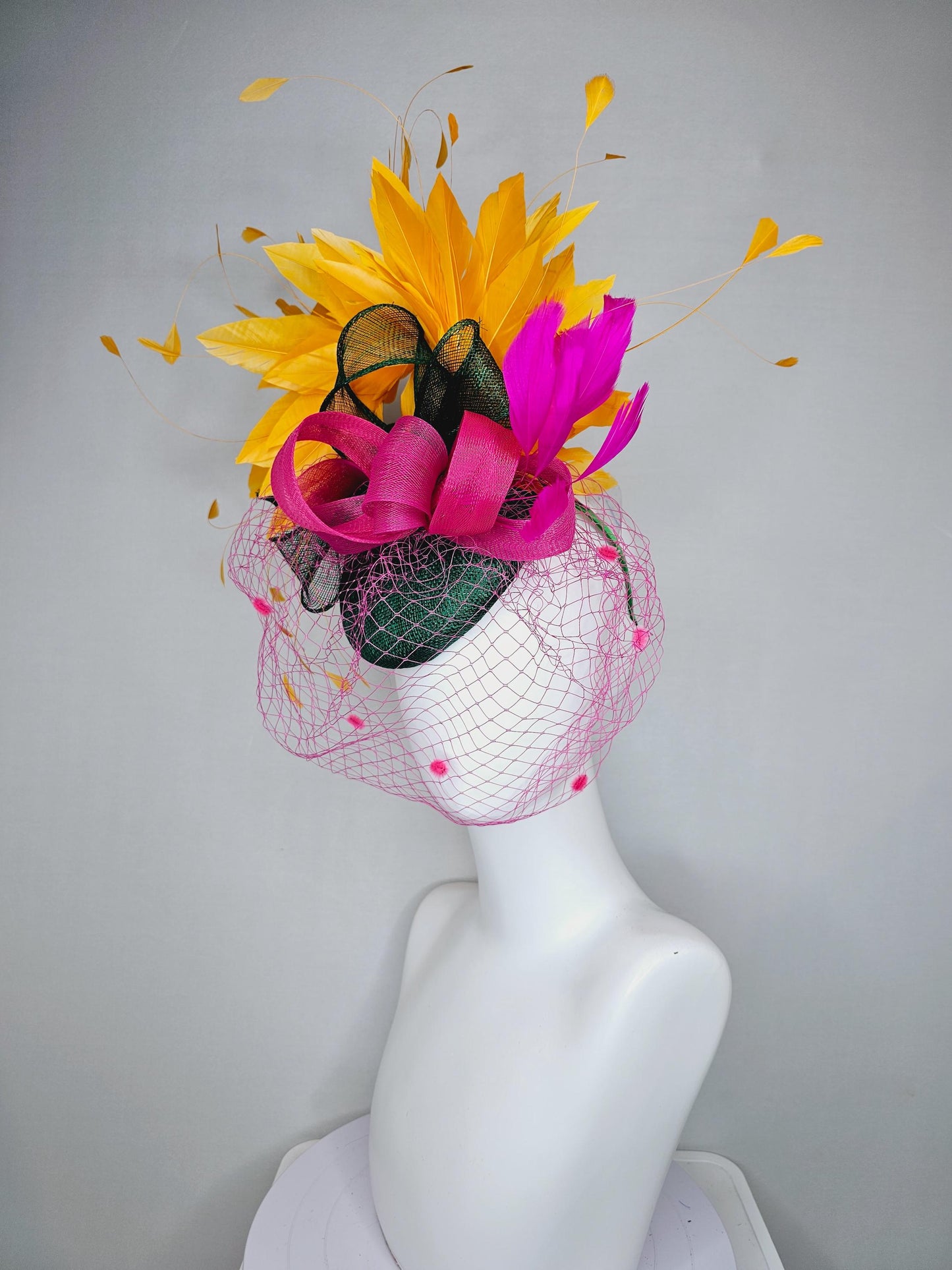 kentucky derby hat fascinator dark green sinamay with dark green and pink sinamay bow pink and yellow feathers and pink mesh veil