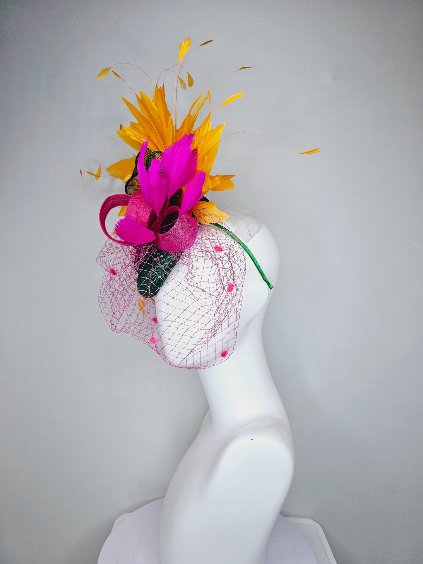 kentucky derby hat fascinator dark green sinamay with dark green and pink sinamay bow pink and yellow feathers and pink mesh veil