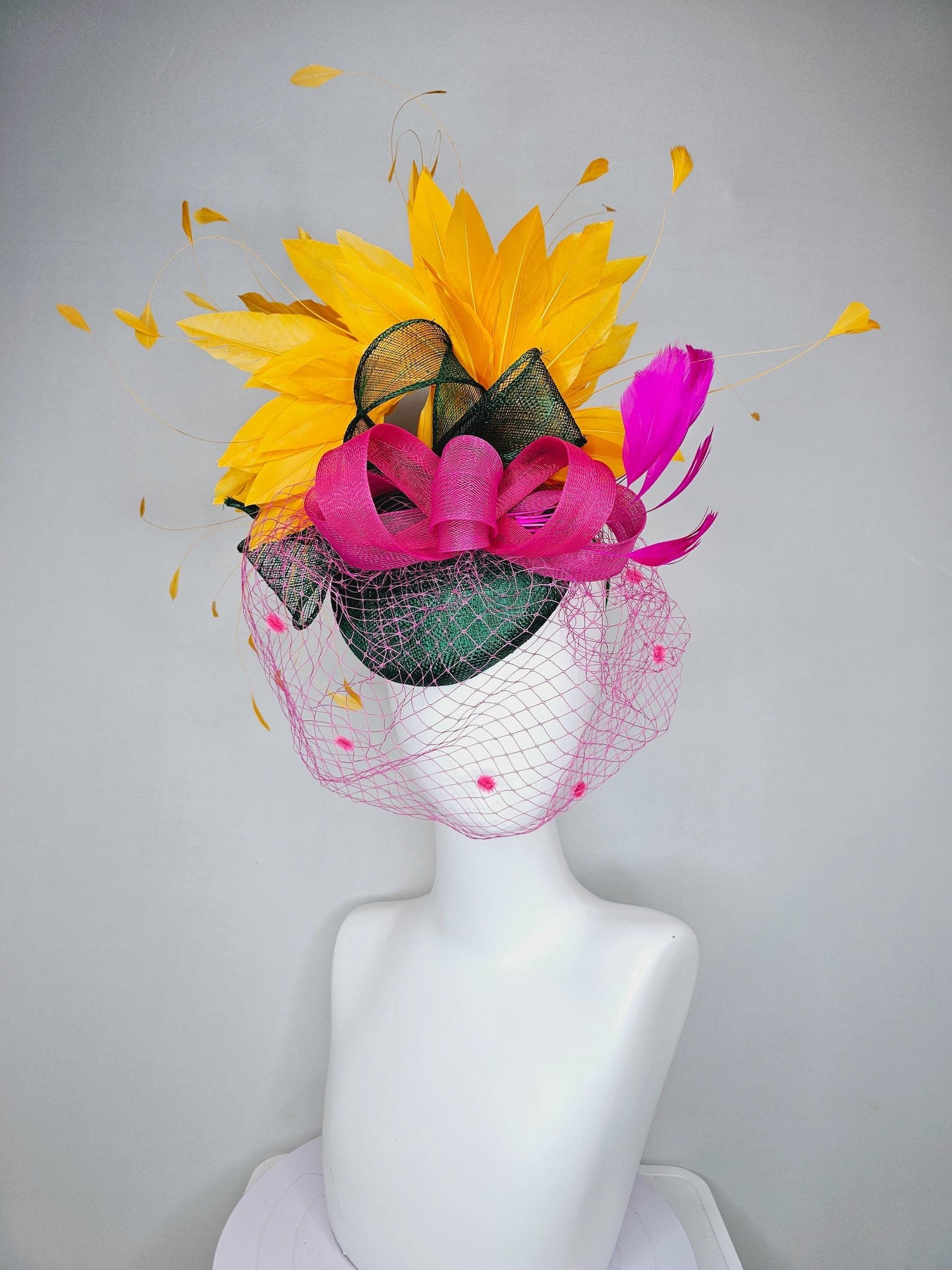 kentucky derby hat fascinator dark green sinamay with dark green and pink sinamay bow pink and yellow feathers and pink mesh veil