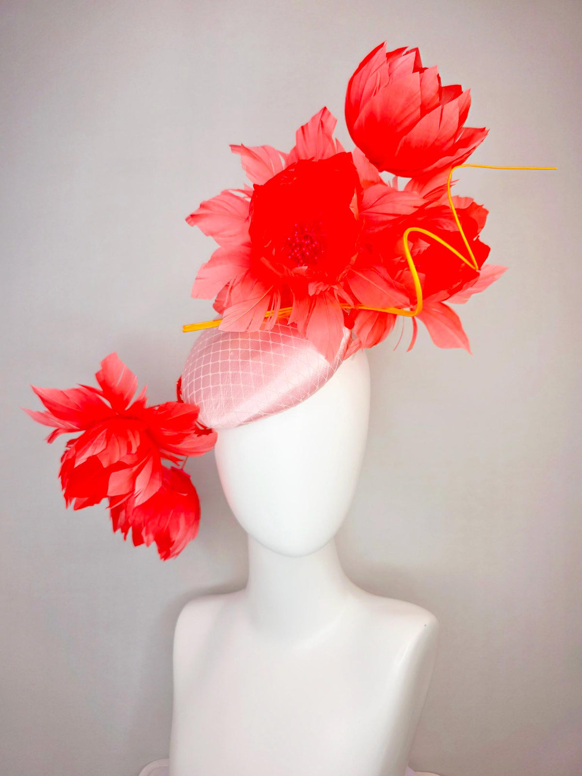 kentucky derby hat fascinator light pink satin with netting and large fluffy coral red feather flowers and light peach orange feathers
