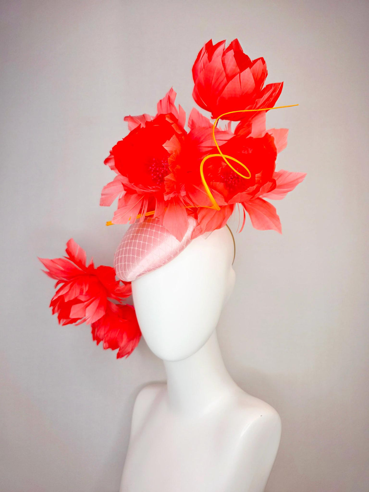 kentucky derby hat fascinator light pink satin with netting and large fluffy coral red feather flowers and light peach orange feathers