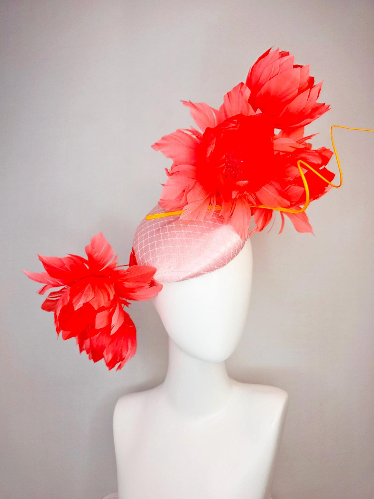 kentucky derby hat fascinator light pink satin with netting and large fluffy coral red feather flowers and light peach orange feathers