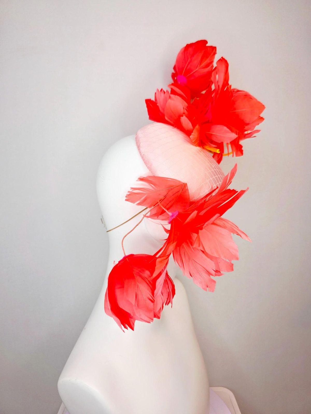 kentucky derby hat fascinator light pink satin with netting and large fluffy coral red feather flowers and light peach orange feathers
