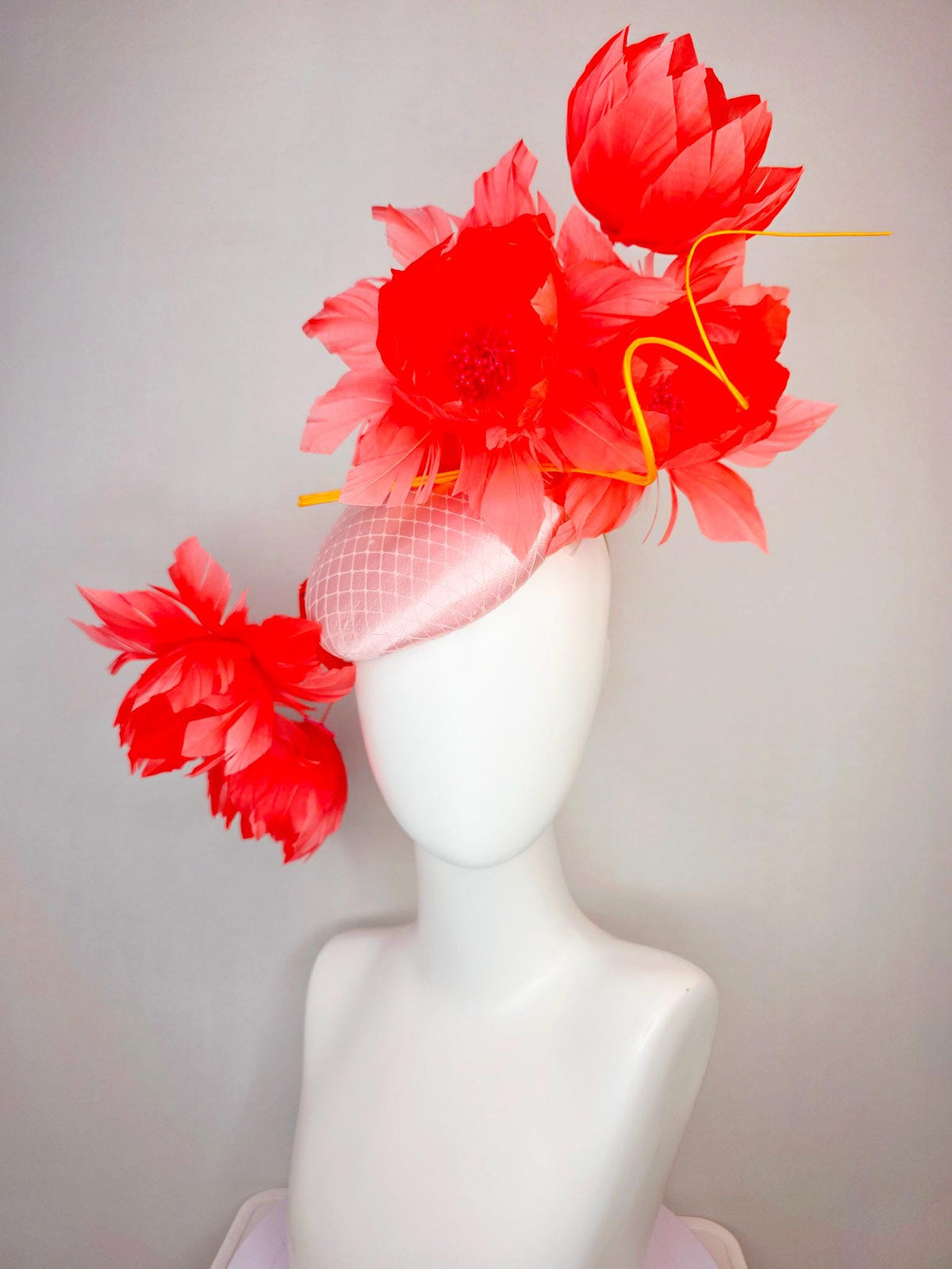 kentucky derby hat fascinator light pink satin with netting and large fluffy coral red feather flowers and light peach orange feathers