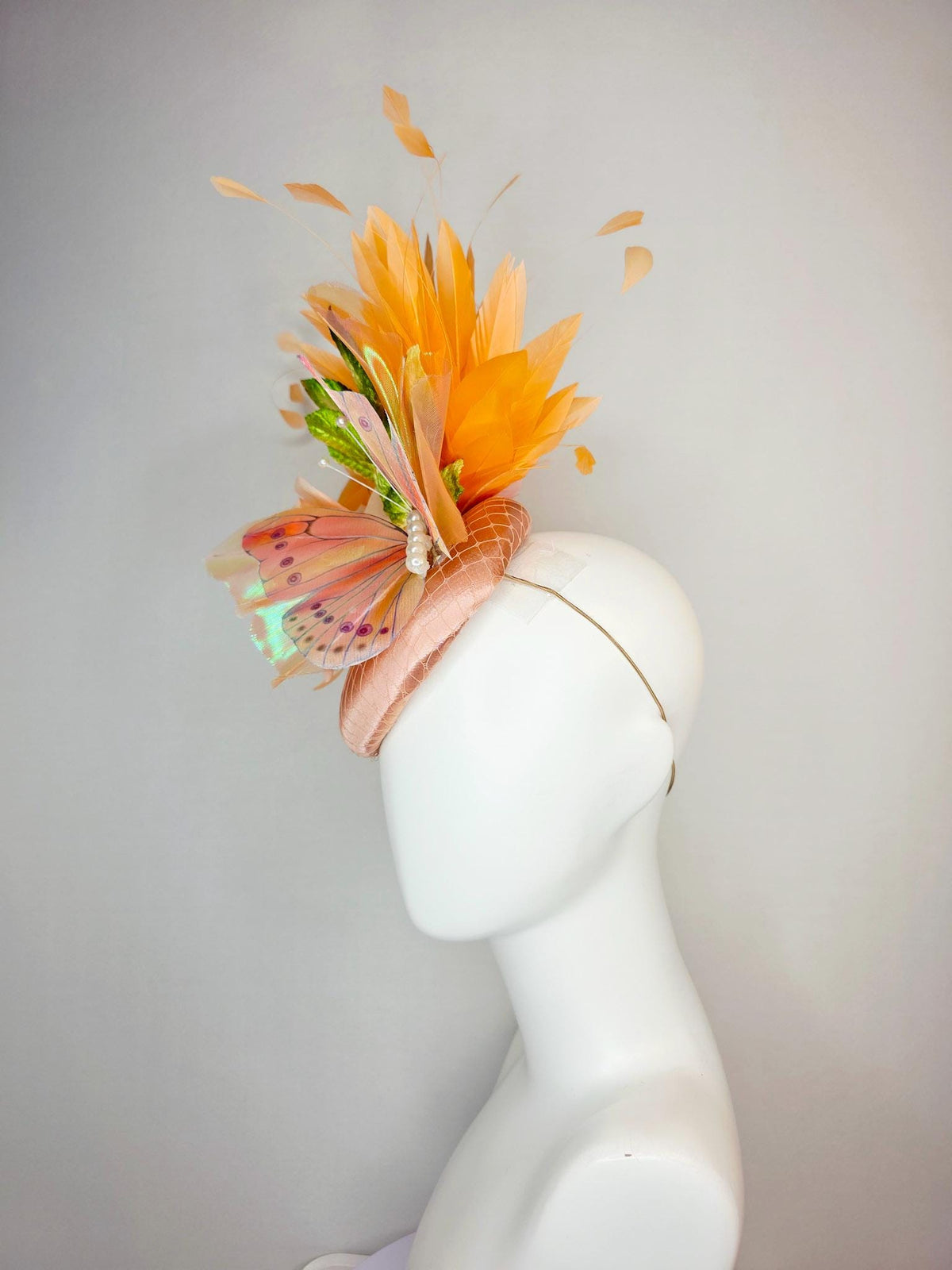 kentucky derby hat fascinator champagne pink satin with netting light pink satin rose green leaves burnt orange feathers and large butterfly