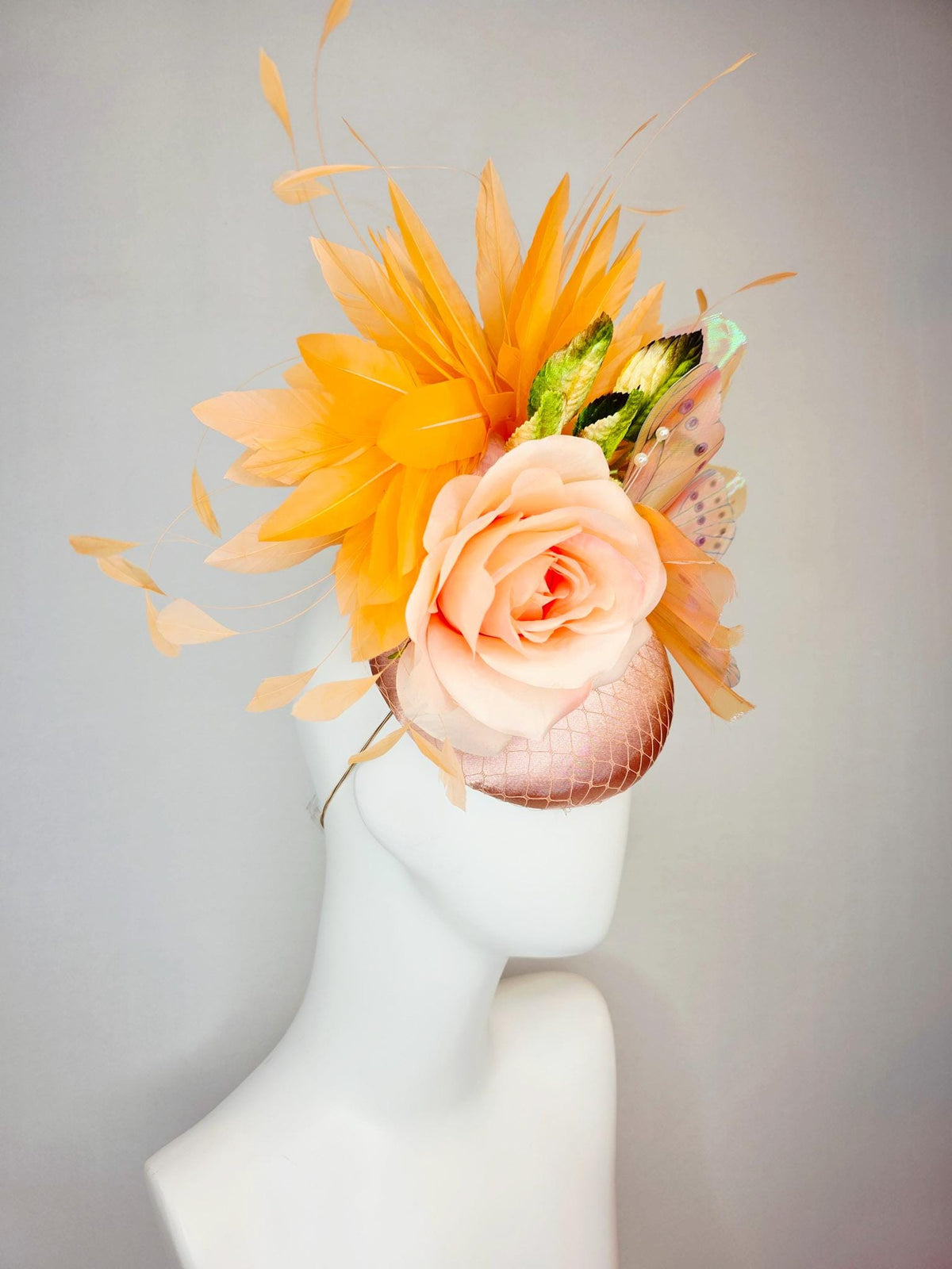 kentucky derby hat fascinator champagne pink satin with netting light pink satin rose green leaves burnt orange feathers and large butterfly