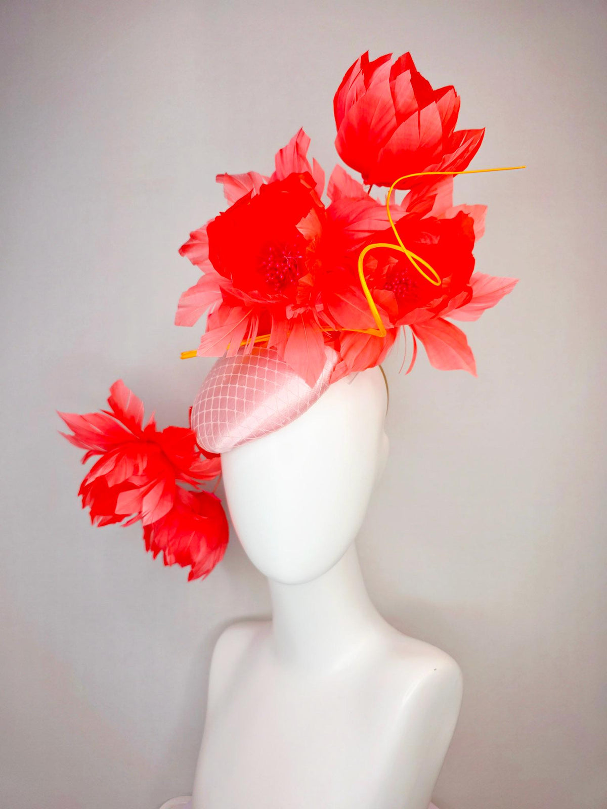 kentucky derby hat fascinator light pink satin with netting and large fluffy coral red feather flowers and light peach orange feathers