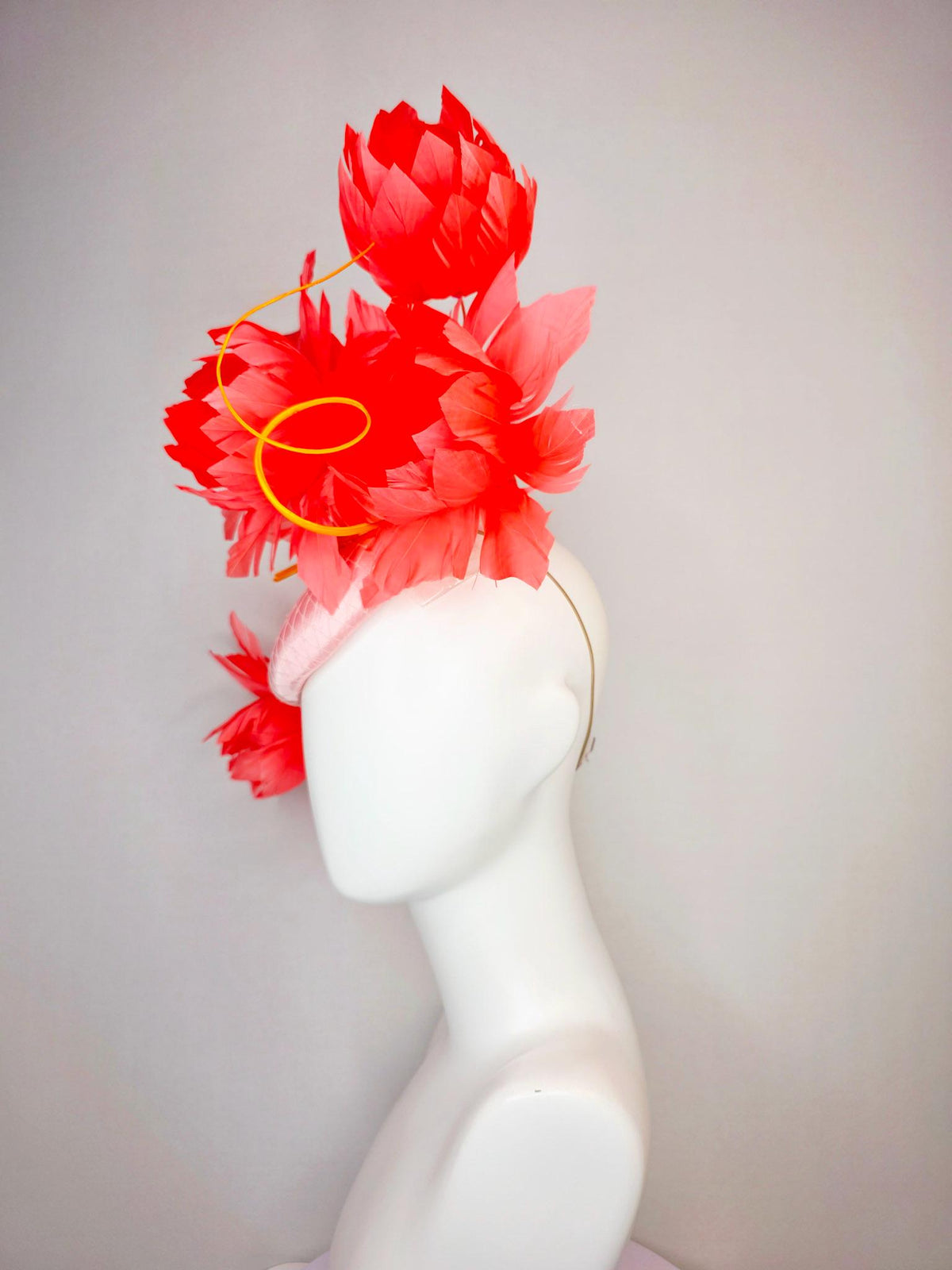 kentucky derby hat fascinator light pink satin with netting and large fluffy coral red feather flowers and light peach orange feathers